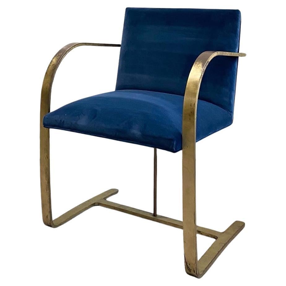 Striking set of four Brno armchairs, reupholstered in a rich sapphire blue cotton velvet that adds depth and luxury to the minimalist silhouette. These chairs are crafted with extremely heavyweight solid brass frames—unlacquered and beautifully