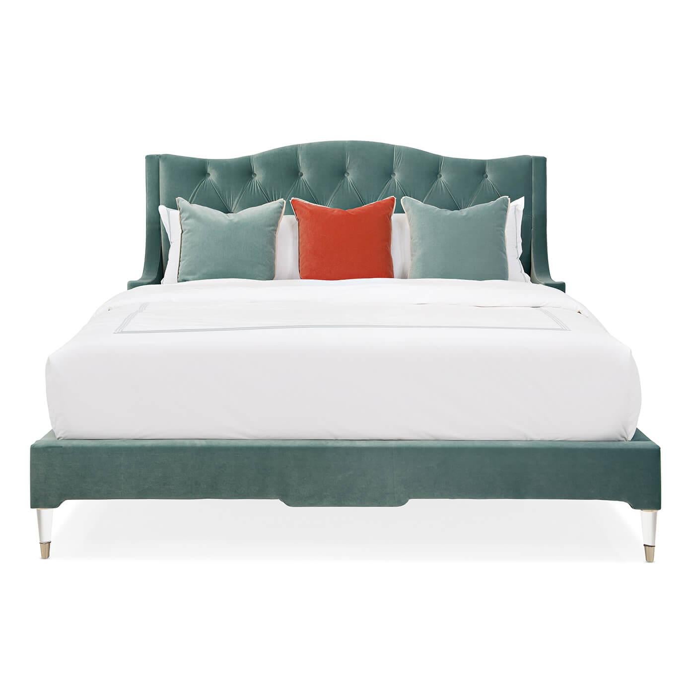A velvet tufted upholstered king bed with a tufted diamond-pattern headboard. This bed is upholstered in a sea-inspired fabric. The sides of the headboard wrap around with a design inspired by an English armchair. It has wooden legs finished in