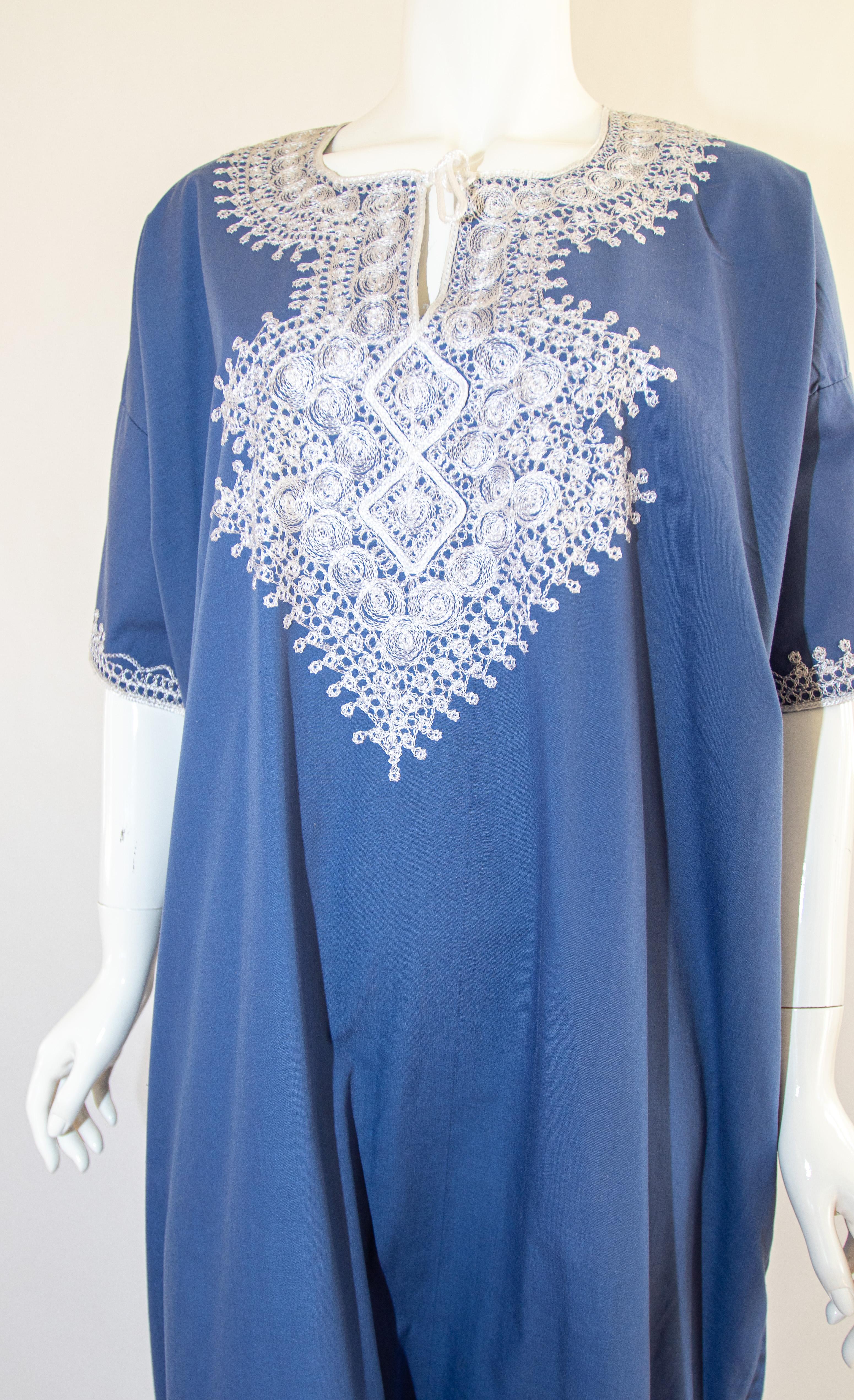 Caftan marocain bohème de couleur bleue brodé de fils blancs.
vers les années 1980.
Cette longue robe maxi en coton kaftan d'été est brodée de motifs mauresques traditionnels.
Le kaftan présente une encolure traditionnelle, avec des fentes latérales