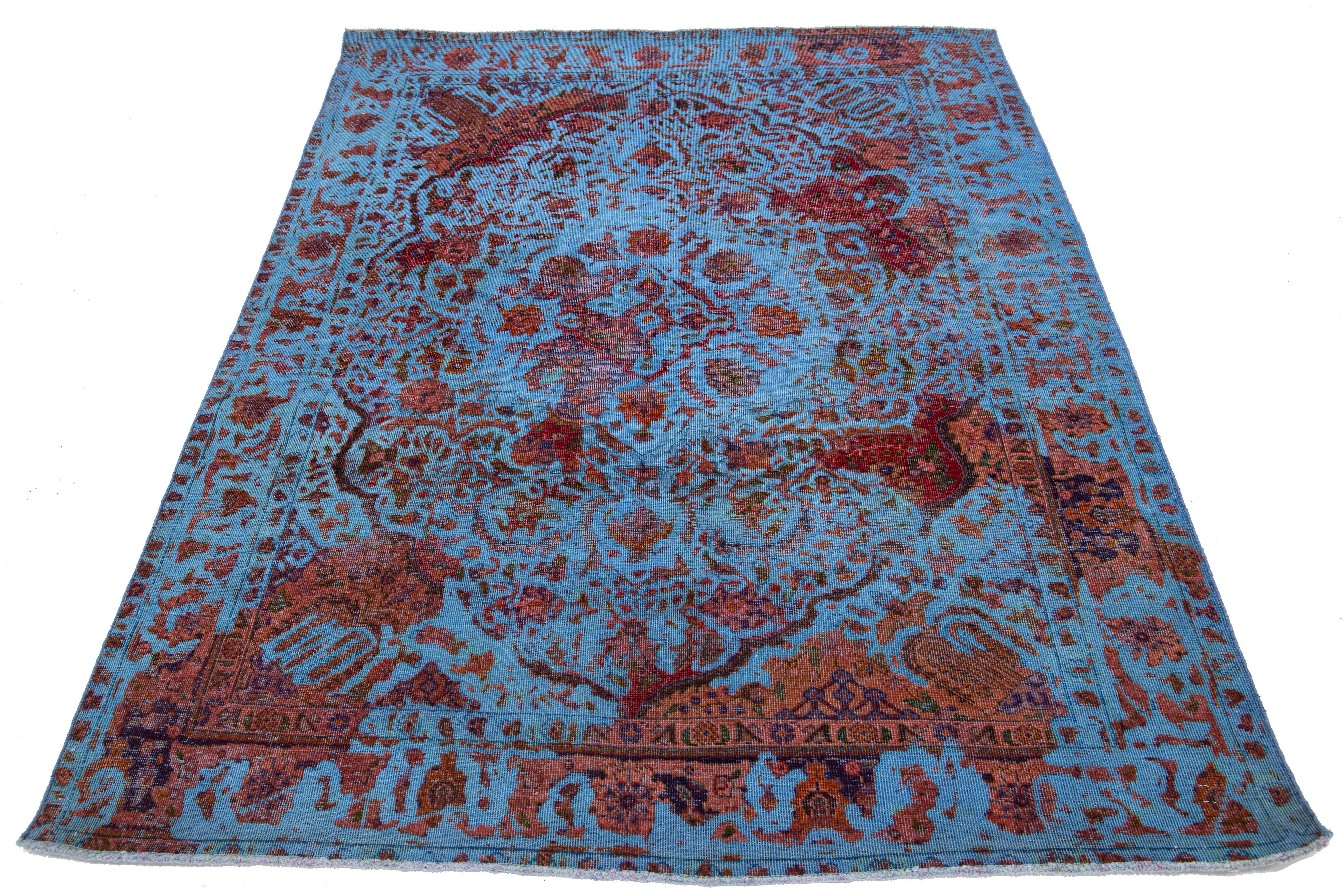 Dieser exquisite Teppich aus persischer Wolle im Vintage-Stil besticht durch sein blaues Feld, das mit charmanten rostigen Blumenakzenten verziert ist.

Dieser Teppich misst 4'7