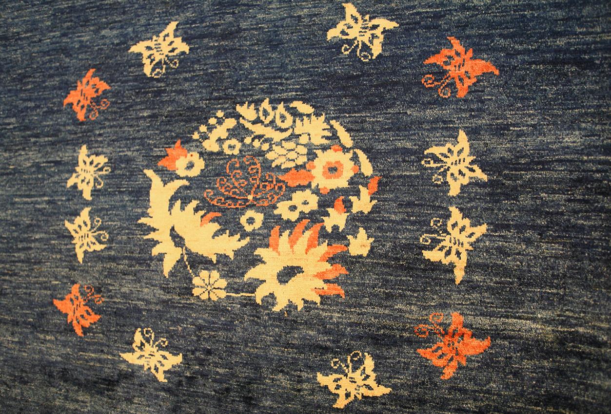 This is a Blue Vintage Yadan rug woven in Pakistan during the 21th century. The field is designed with minimalist elements and It also features beautiful butterflies flying around the central flowers and moreover the border has a fantastic touch of