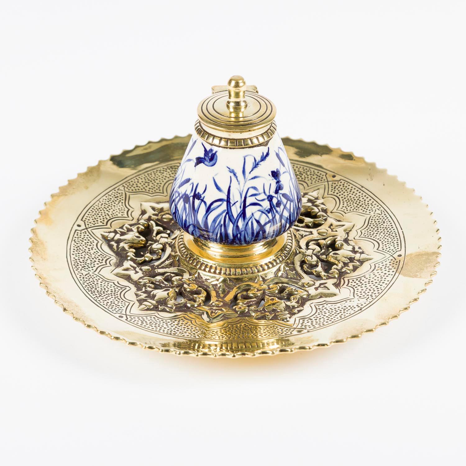 A late 19th century blue and white ceramic inkwell with circular pierced brass stand and brass lid.

They ceramic inkwell depicts a riverside scene of birds and rushes. 
