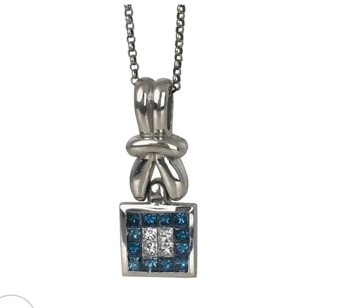 18 karat white gold pendant with princess cut blue and white diamonds. The excellently styled pendant is vibrant blue colored with accenting white diamonds in the center.

The pendant hangs 1-1/2 x ½ inches in diameter and consists of ˜Invisible set