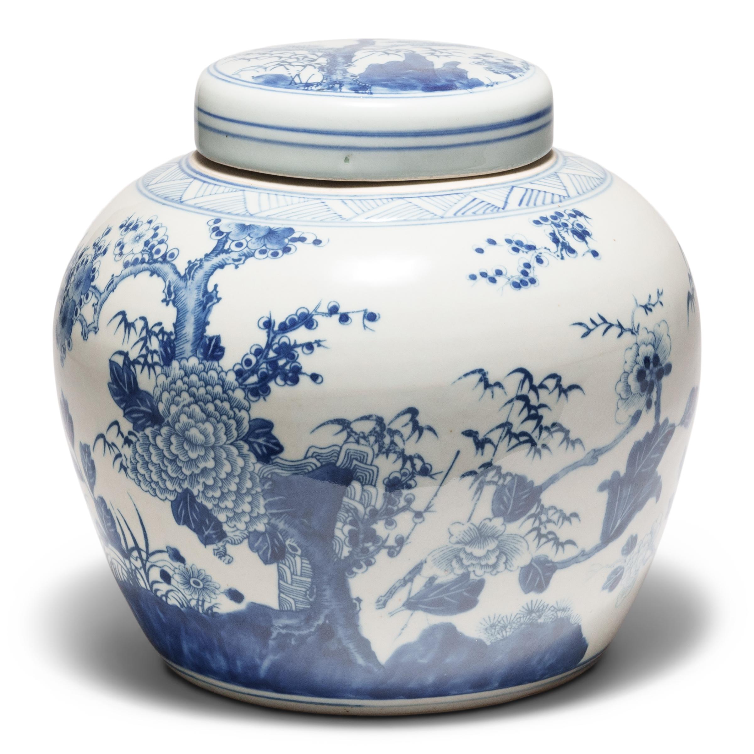 Ce pot à gingembre rond en porcelaine est brillamment émaillé dans le style bleu et blanc. Combinant un travail au pochoir et un ombrage brossé à la main, la jarre est décorée d'un paysage de jardin avec les fleurs des quatre saisons. Ancrée par des