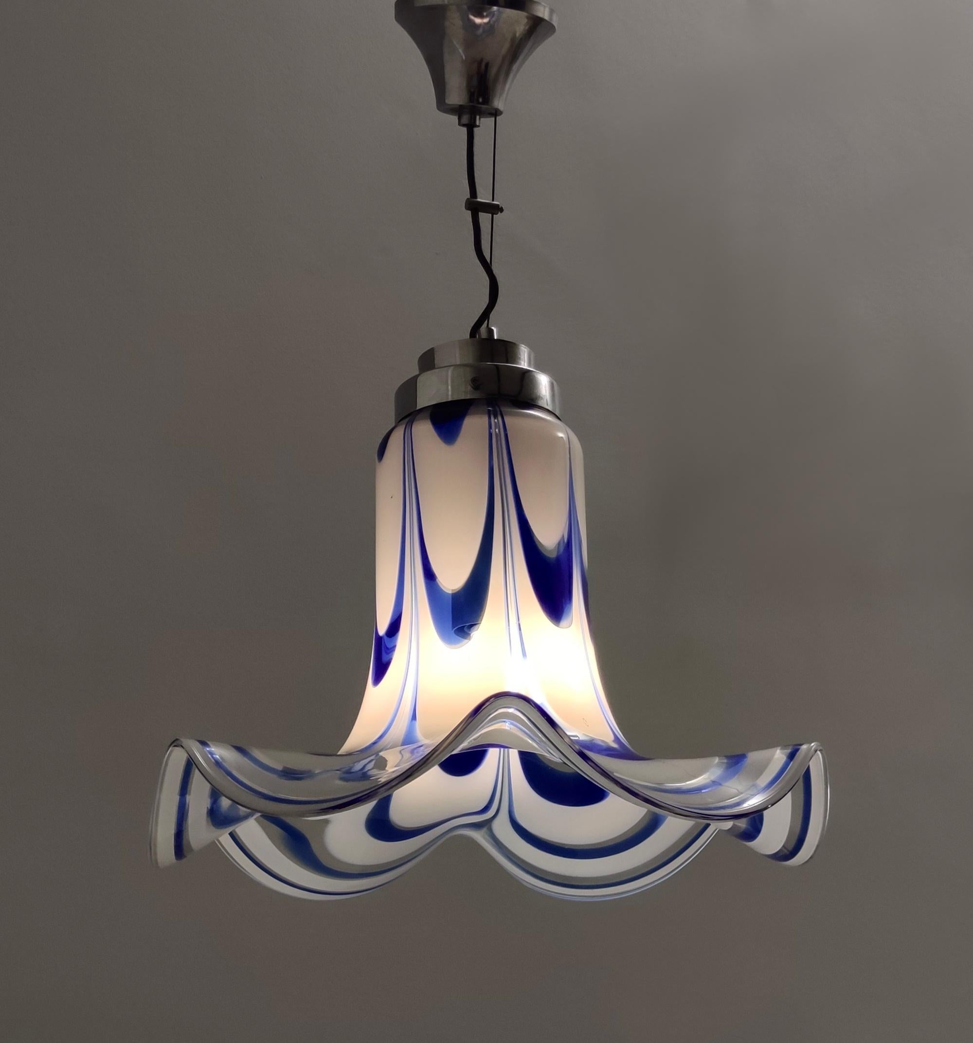Fabriqué en Italie, années 1970. 
Cette suspension est dotée d'un abat-jour en forme de cloche en verre de Murano bleu et blanc.
Il s'agit d'une pièce d'époque, qui peut donc présenter de légères traces d'utilisation, mais qui peut être considérée