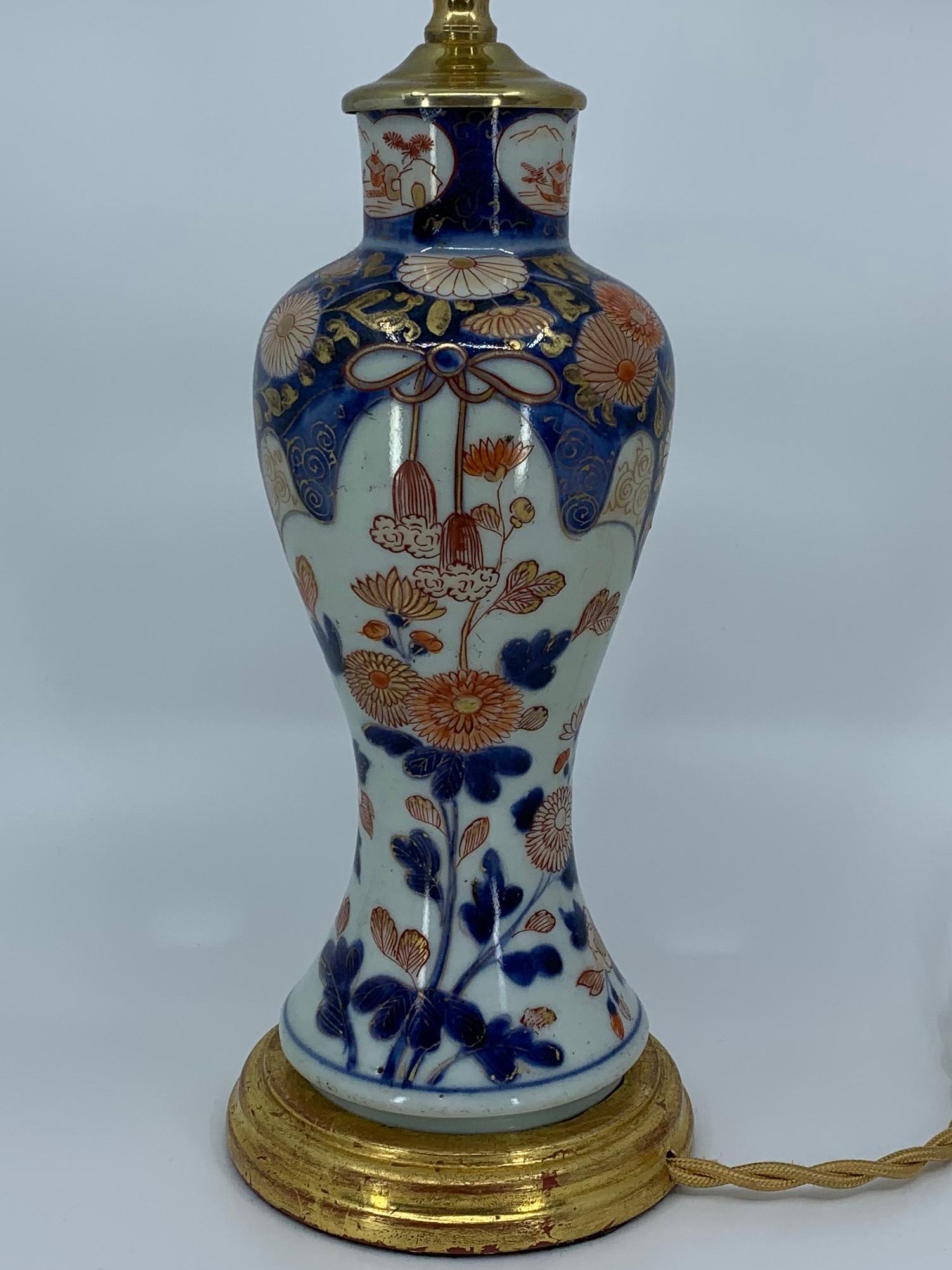 Blue, white, red and gilt porcelain lamp on water giltwood base. Chinese porcelain vase converted into a lamp in blue, white, red and gilt floral on water gilt base. Newly electrified with gold silk with switch. China, late 19th century
Dimensions: