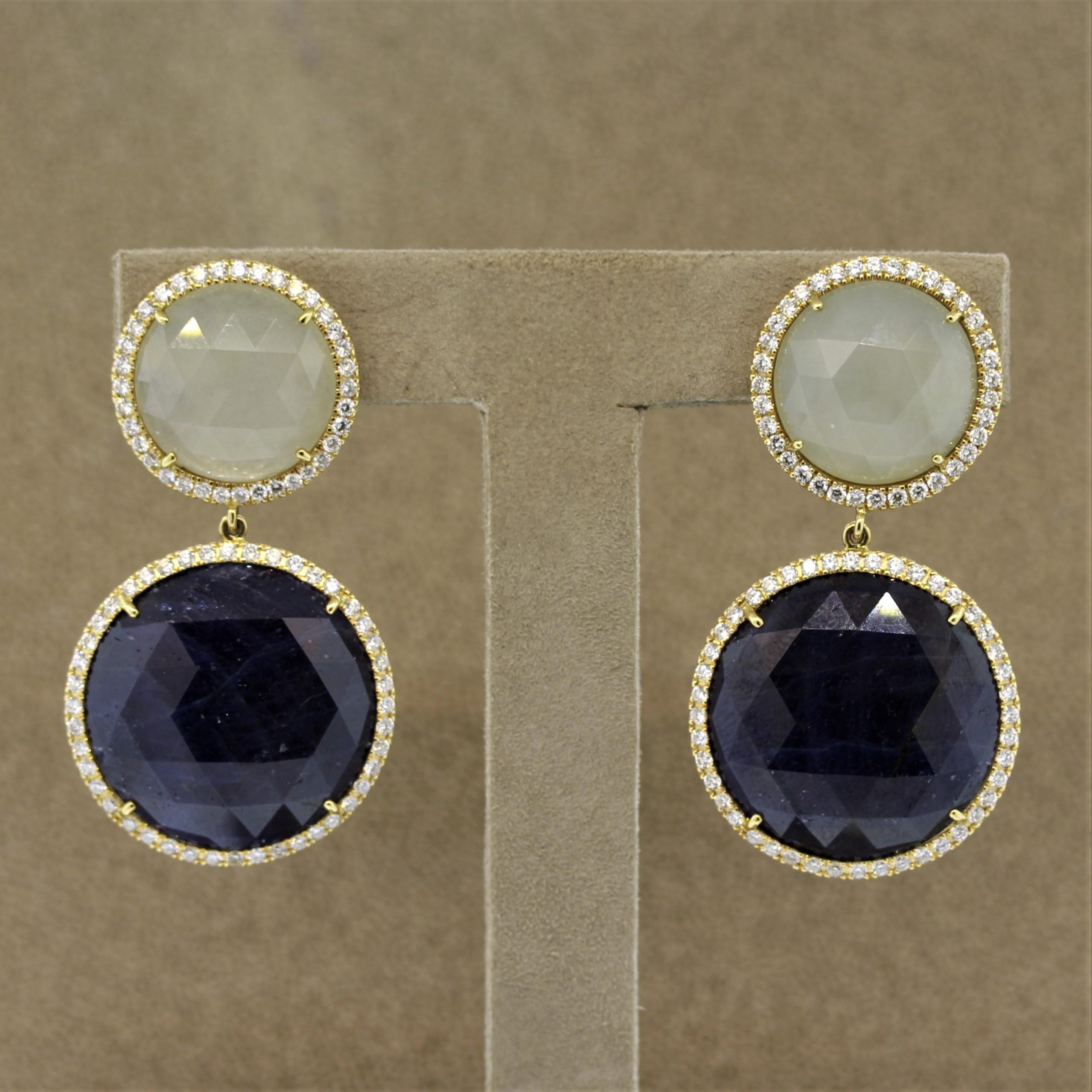 A unique pair of earrings featuring a total of 60 carats of sapphire! Each earring has a larger blue sapphire set below a white sapphire which are all rose cut. There are 3.00 carats of round brilliant cut diamonds set in 18k gold which halo the
