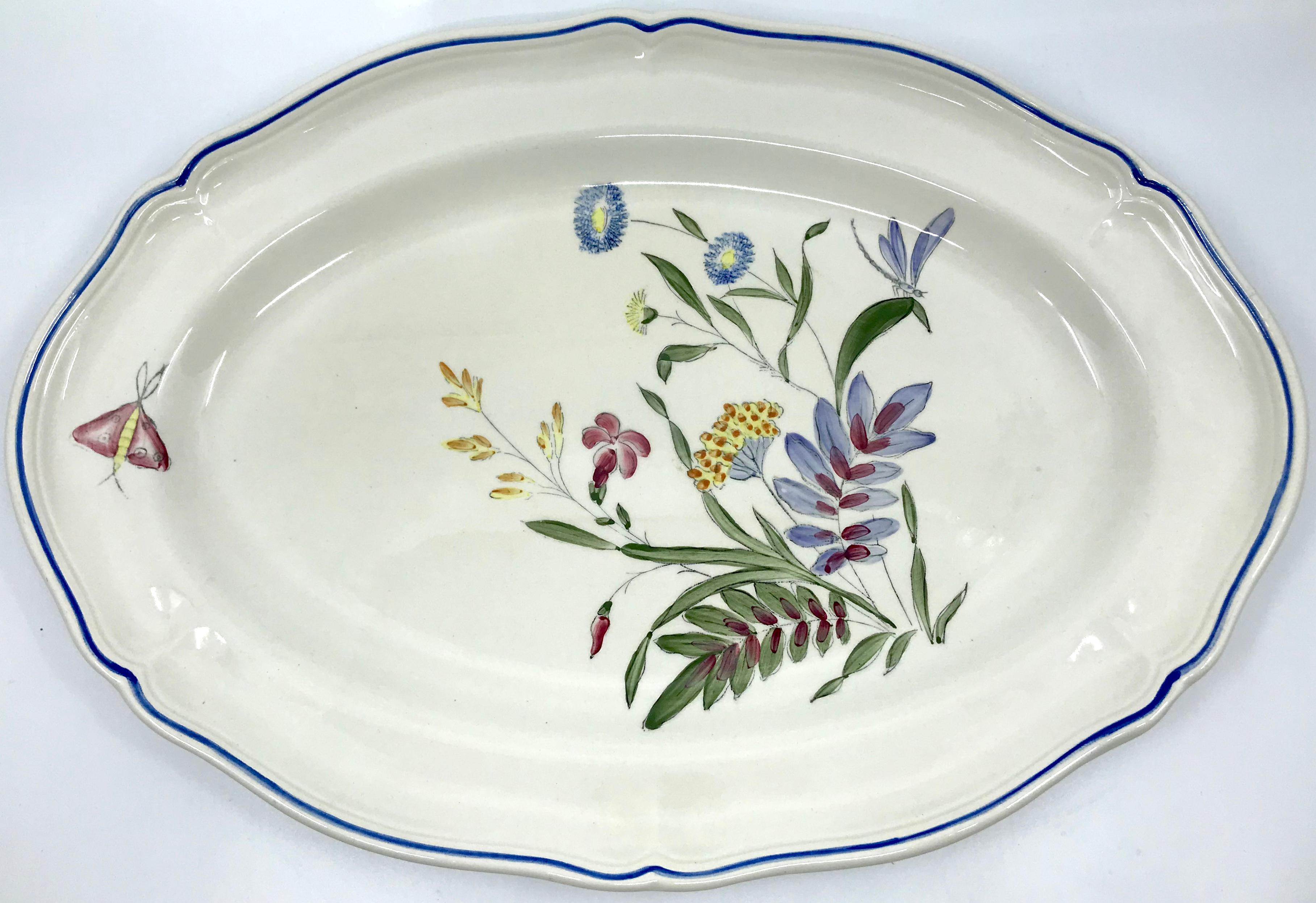 Blue, white, yellow and magenta floral platter. Blue rimmed and shaped border ovoid platter with hand painted country floral sprig in greens, yellow blue and magenta with butterfly. Longchamps factory. France, mid 20th century
Dimensions: 16.5