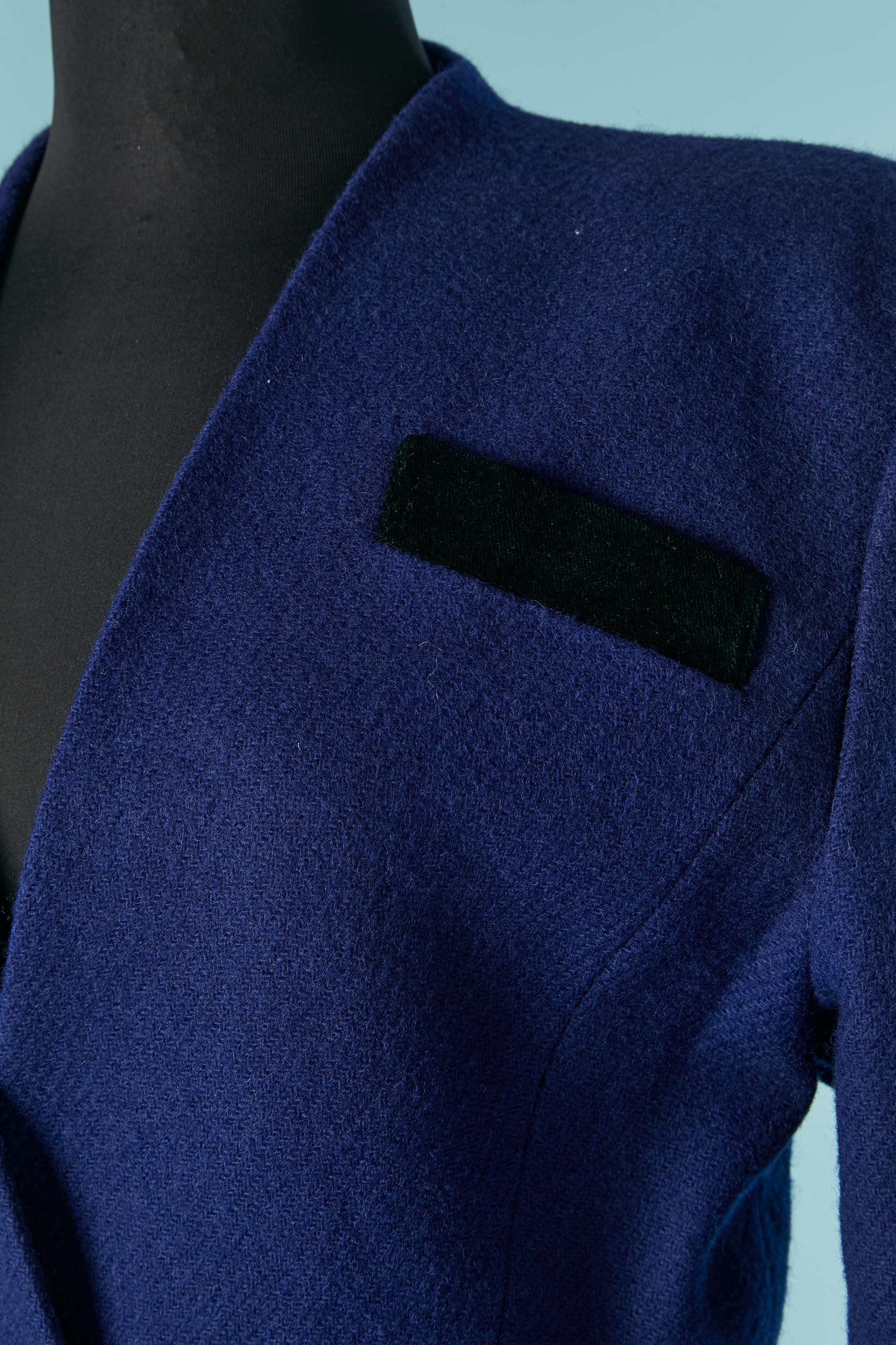 Combinaison jupe en laine bleue avec détails en velours noir. Doublure en acétate ou en rayonne. 
Pad d'épaule. Fermeture à un bouton (recouvert de tissu) sur le milieu du devant. 4 poches sur le devant. 
TAILLE de la veste 42 (Fr) L 
TAILLE de la