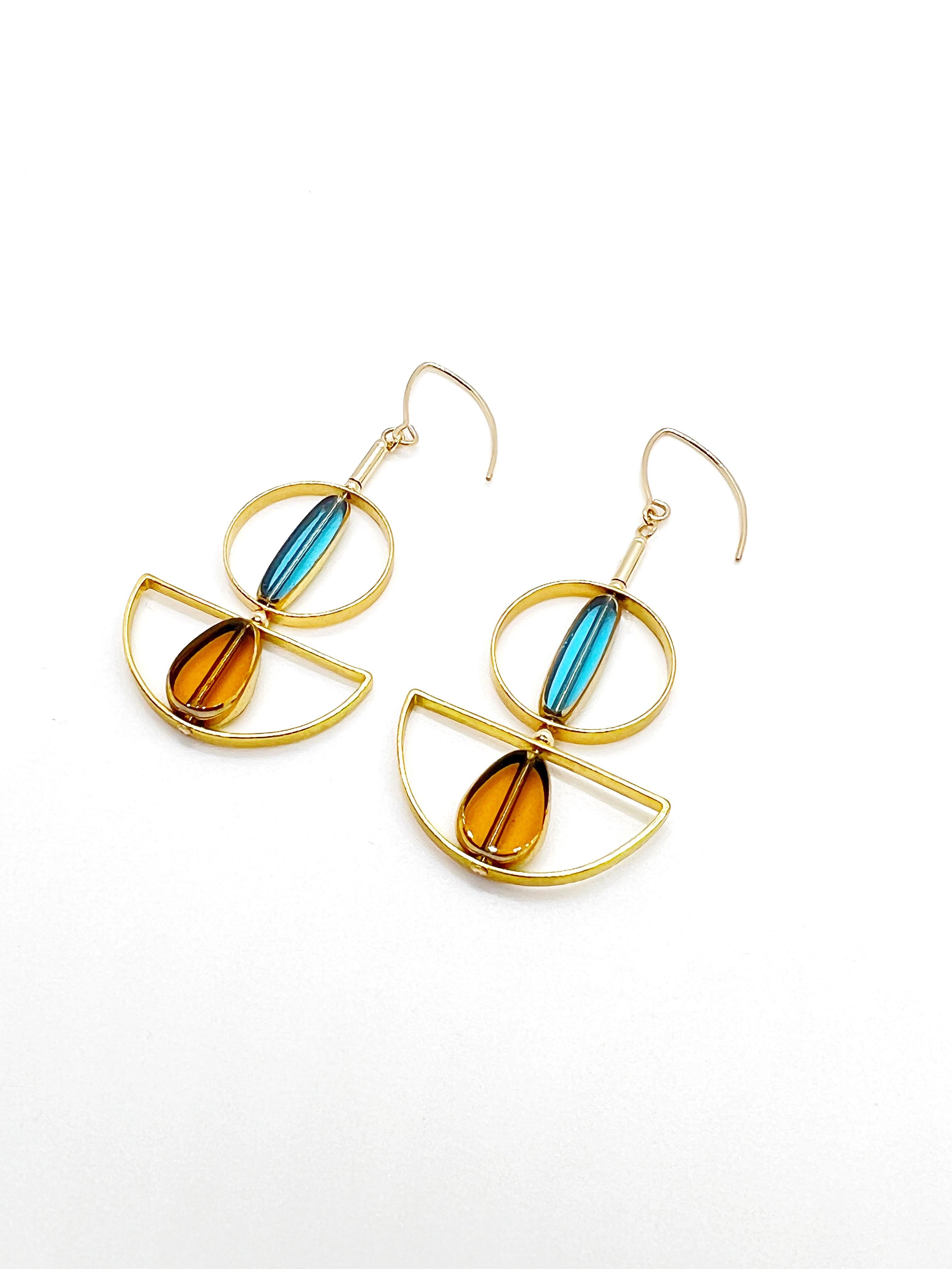 The earrings are light weight and are made to rotate and reposition with movement.

The earrings consist of a blue and yellow shaped beads. They are new old stock vintage German glass beads that are framed with 24K gold. The beads were hand pressed