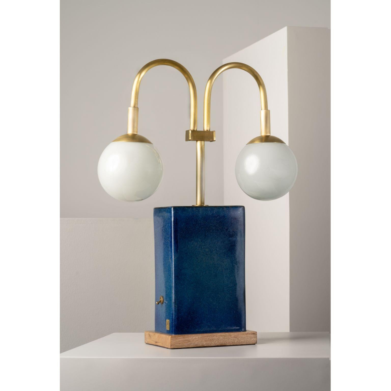 Blue Yeye Table Lamp by Isabel Moncada
Dimensions: Ø 40.5 x H 53.5 cm.
Materials: Stoneware ceramic and solid wood base, hand-forged brass and blown glass globes.

As deep as space, the indigo-blue stoneware ceramic base is coupled with double