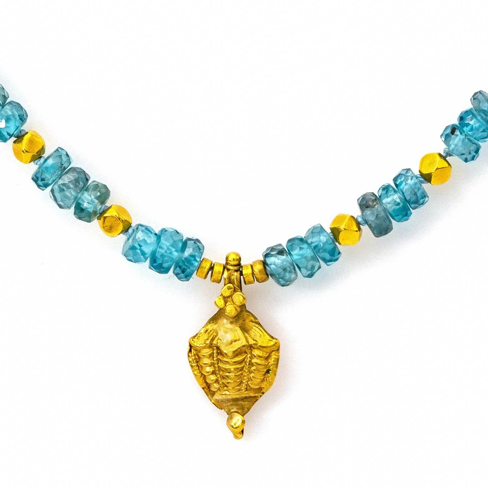 This stunning blue zircon hand knotted necklace is accented with 18k gold beads and a hand carved pendant that is a lovely delicate shape. The faceted  deep peacock stones sparkle and dazzle in any light to beautifully frame any neckline.The chain