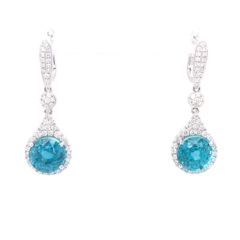 One pair of blue zircon and diamond dangle 18K white gold earring featuring two prong-set, round brilliant cut blue zircon totaling 9 ct. (4.50 ct. each). Enhanced by 102 round brilliant cut diamonds totaling 0.75 ct. and with posts and backs. Circa