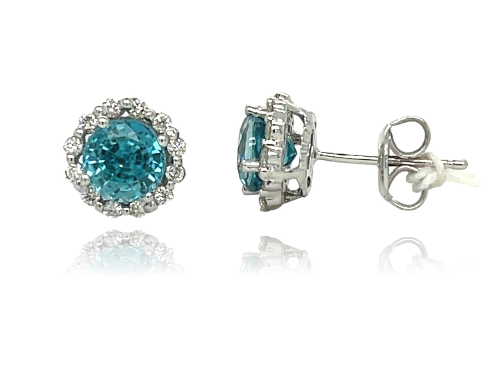 These elegant natural Blue Zircon stud earrings are surrounded by 24 sparkling diamonds and are beautiful to wear everyday. They have 4 prong setting in 18 karat white gold. It is brand new with detailed tags attached. These earrings come in a