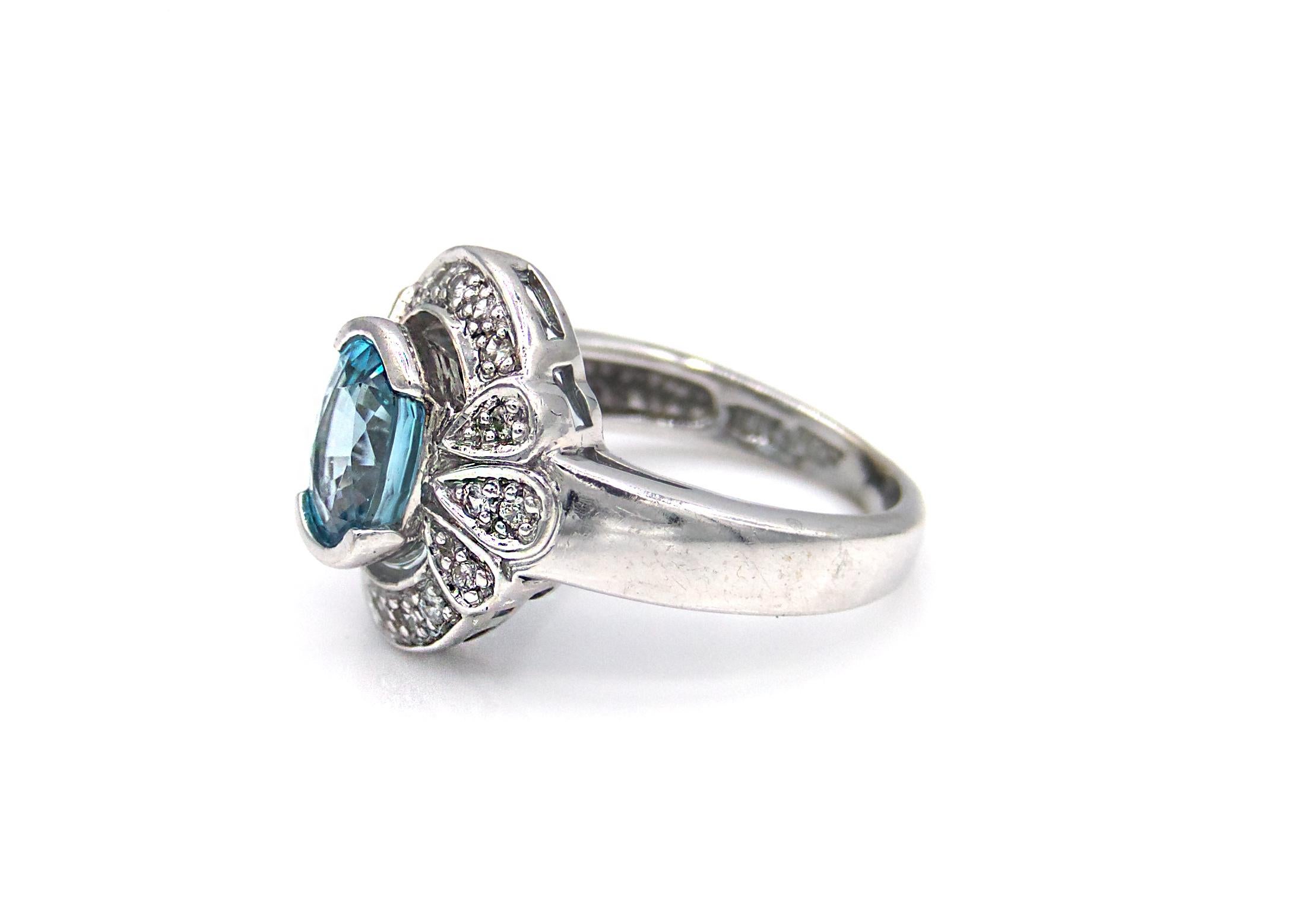 This gorgeous antique-style ring features a 3 Carat oval-cut blue Zircon stone semi bezel set on a 10K White Gold band. The surrounding design is encrusted with numerous glittering pave-cut diamonds. 

5 grams 

Size 5.5 