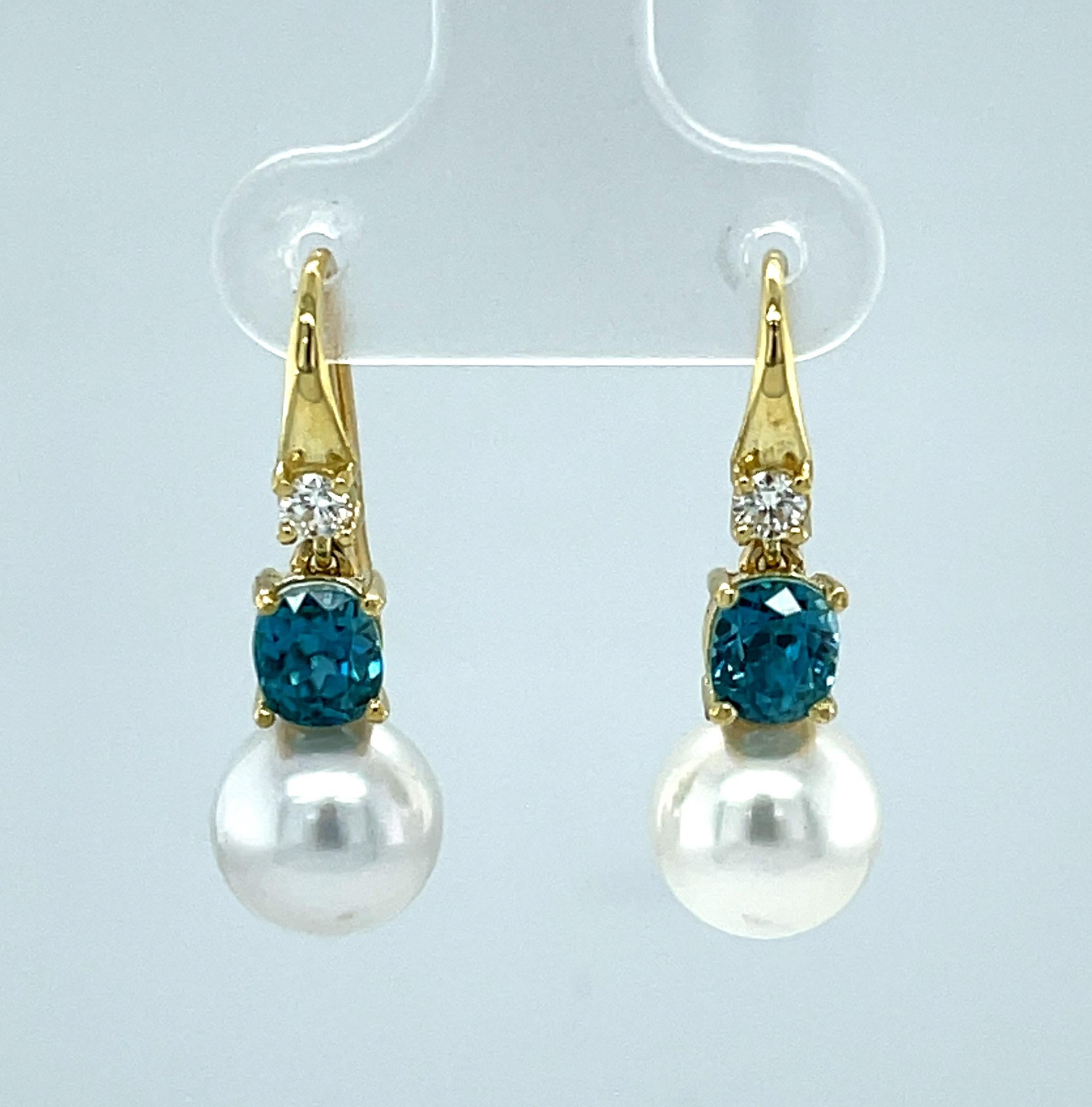 These beautiful dangling earrings feature a pair of gorgeous 9mm South Sea pearls paired with sparkling blue zircon and round brilliant-cut diamonds! Blue zircon gems are known for having exceptional brilliance and luster and this particular pair