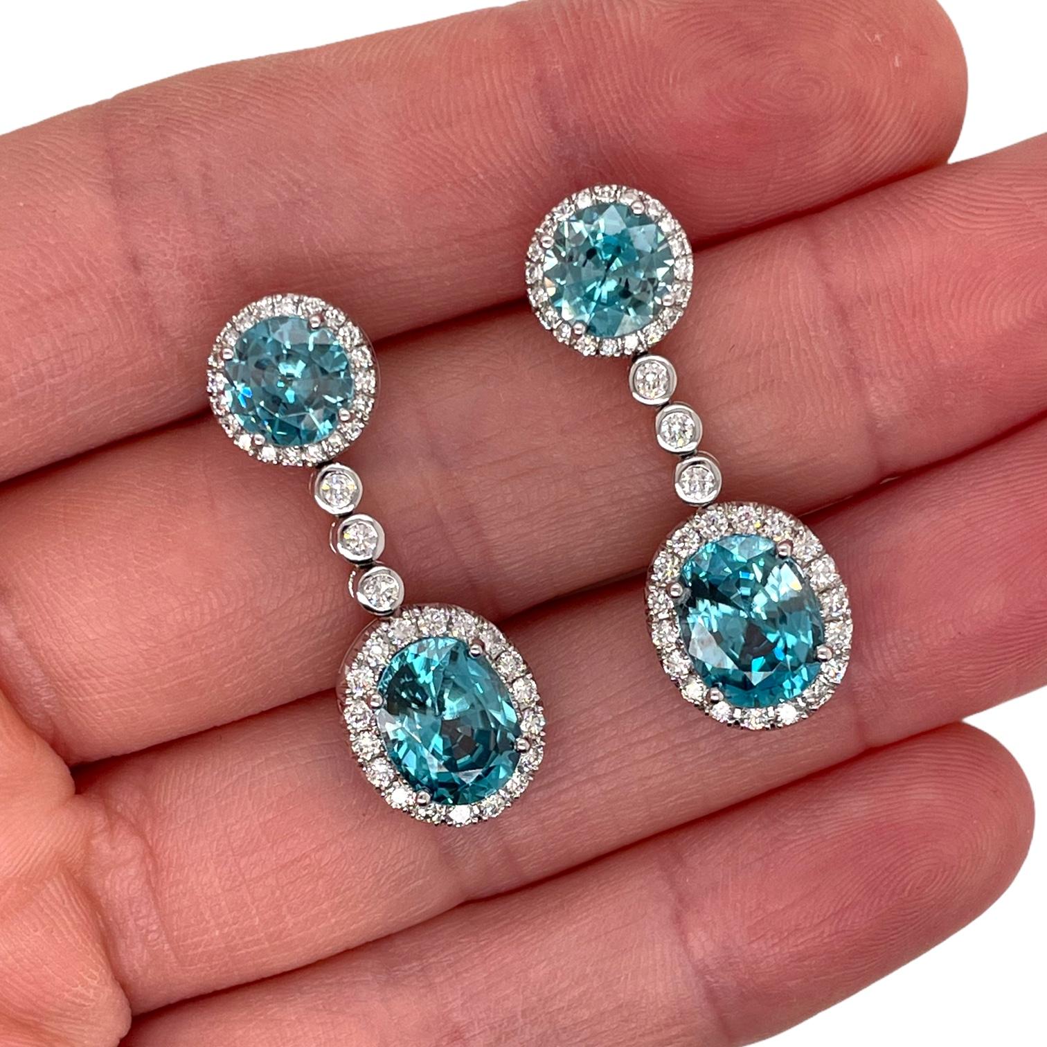 Striking blue zircon and diamond drop earrings in 18k white gold. Earrings contain 2 fine round brilliant & 2 oval cut blue zircons, 10.12tcw and 82 round brilliant diamonds, 0.88tcw. Diamonds are near colorless and SI1 in clarity. Earrings measure
