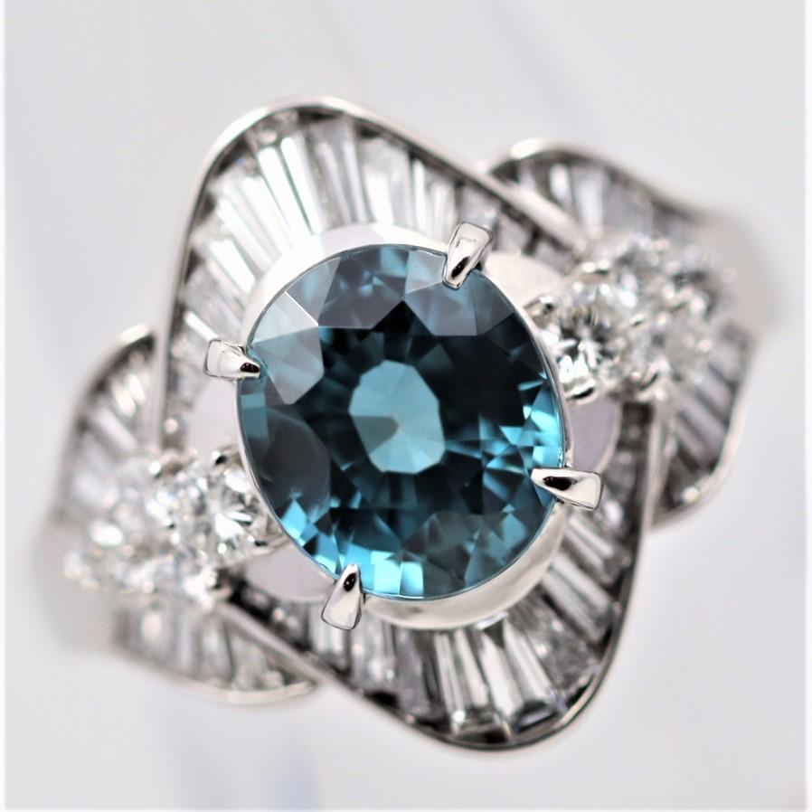 A special piece featuring a 4.84 carat oval-shape zircon with a vibrant rich blue color. It is accented by 1.24 carats of round brilliant and baguette-cut diamonds set in a stylish pattern around the gemstone. Hand-fabricated in platinum and ready
