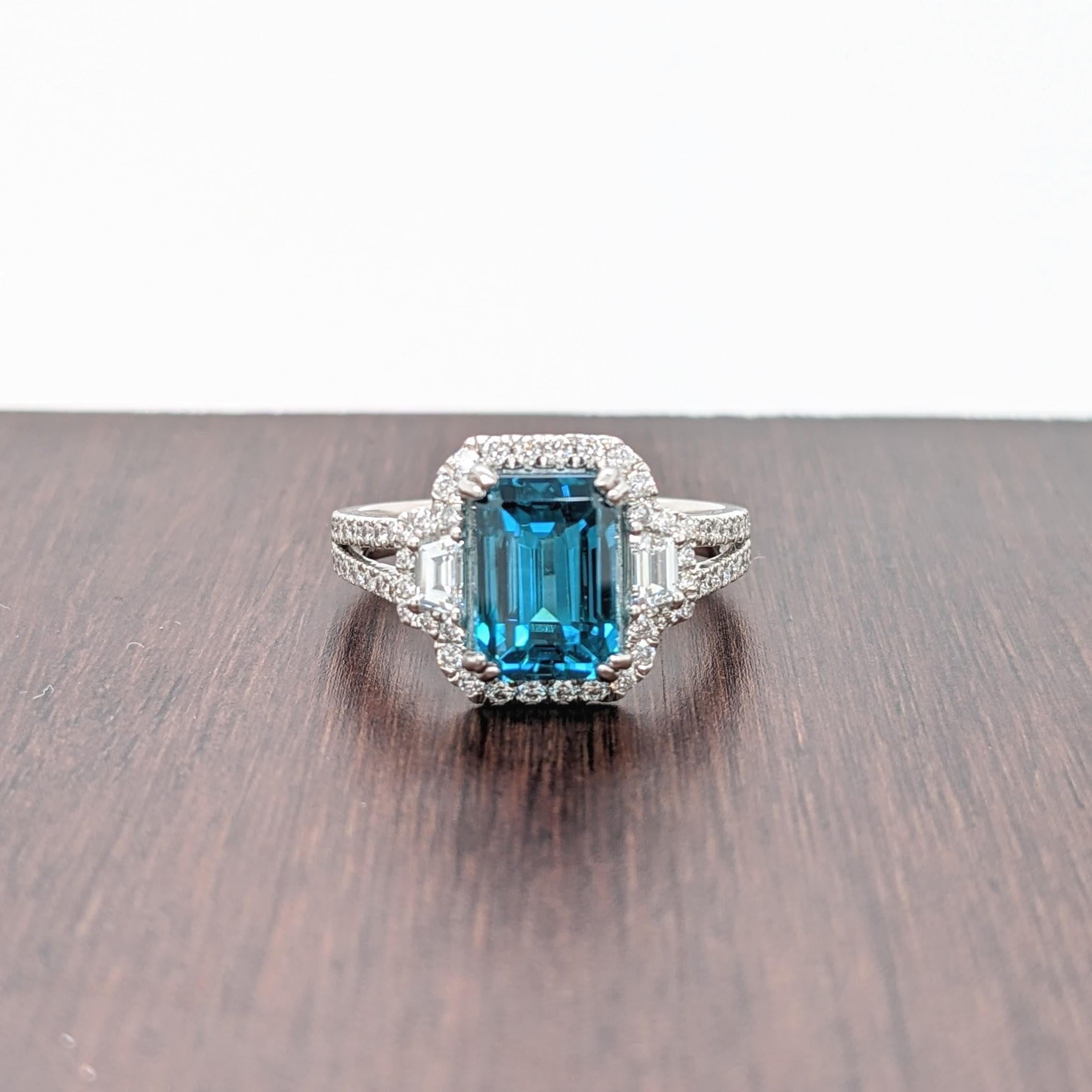 Claim this captivating natural blue zircon for yourself or your loved ones! A masterpiece of nature set in one of our most popular NNJ ring designs made in 14K white gold with a diamond halo and diamond studded split shank. A gorgeous ring for a