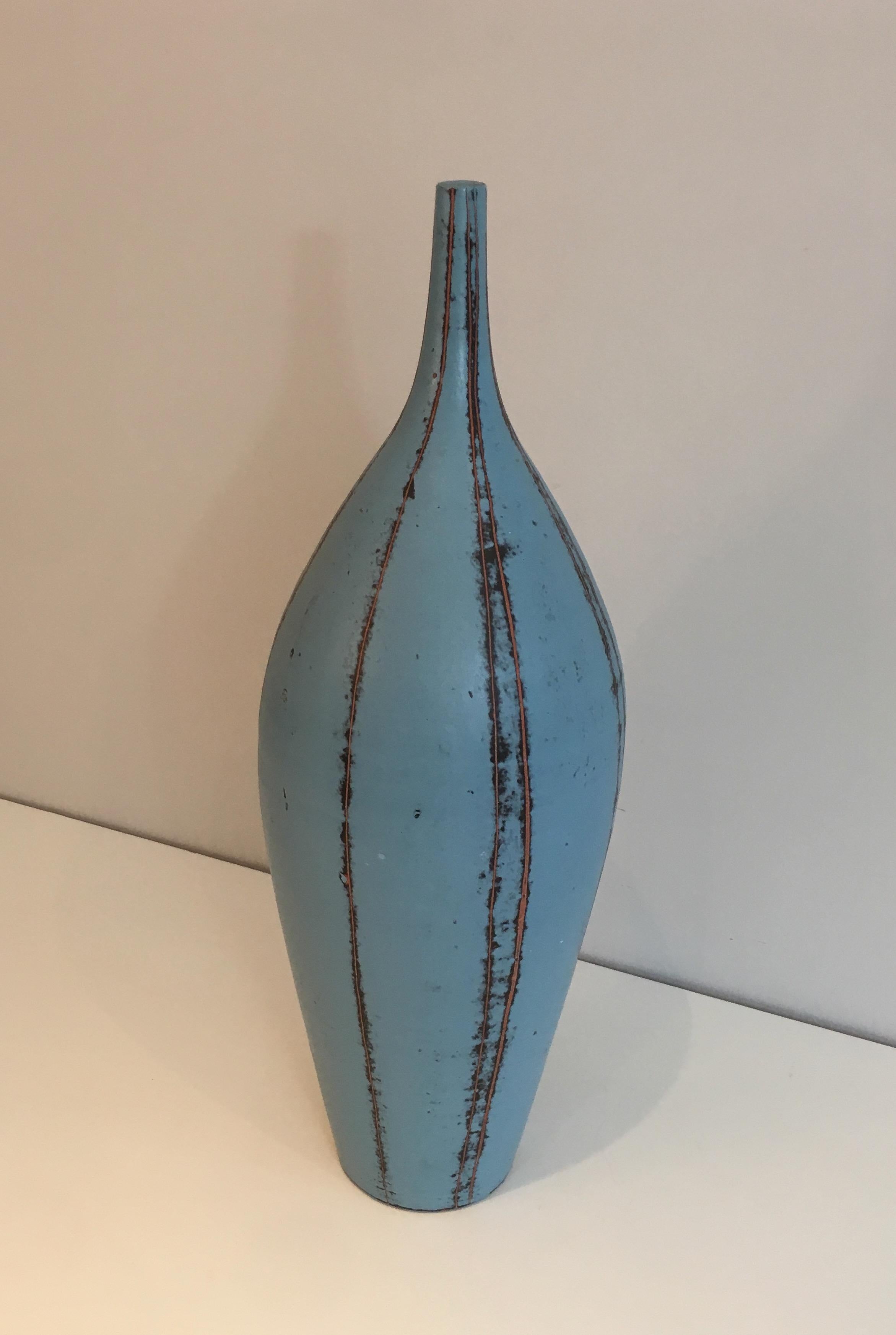 This blueish vase with colored lines is made of ceramic. This is a French work, circa 1970.