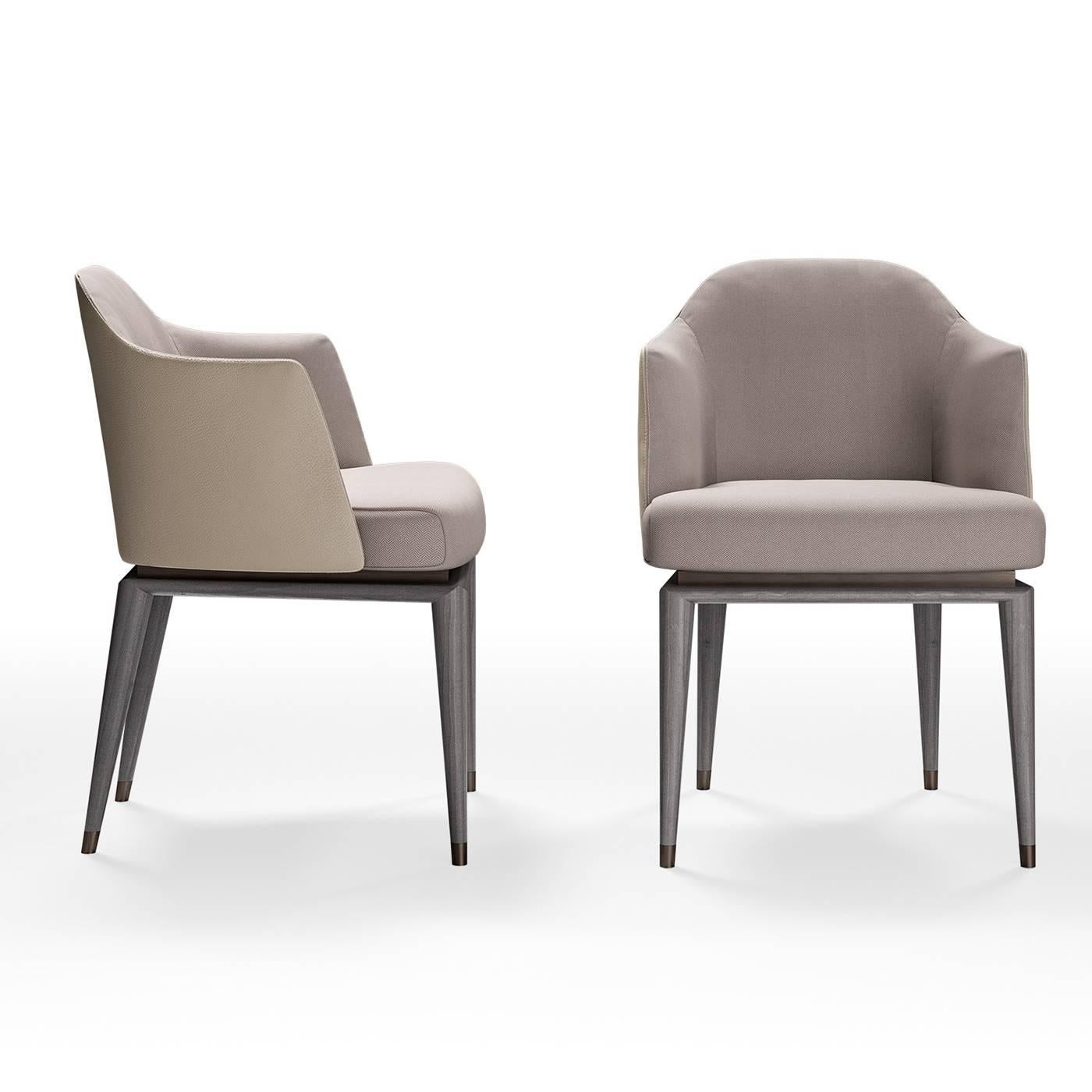 Simple and refined, this contemporary bergère-style armchair exudes comfort and elegance. Supported by four gray, conical feet with brass-finished metal ferules, the elegant frame has closed armrests and is upholstered with gray fabric on the inside