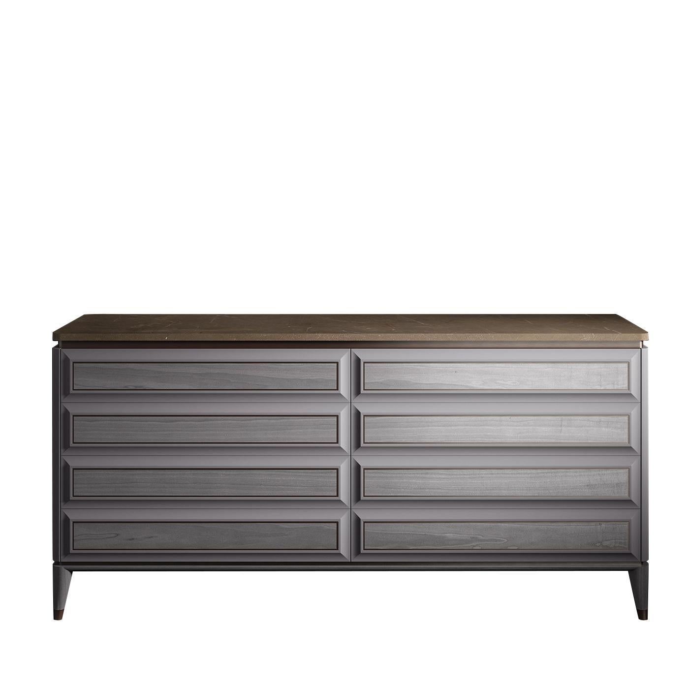 This striking, low-profile dresser is made of wood with a modern gray finish and features eight handle-less drawers with raised front panels that slide effortlessly on metal glides. The Minimalist frame is supported by four conical feet with
