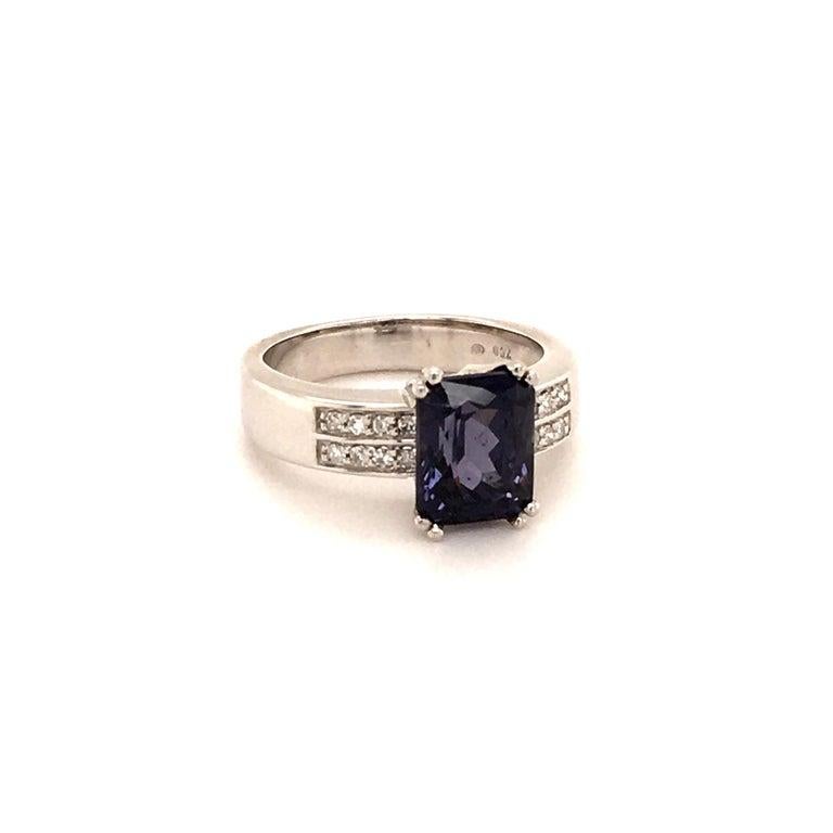 This modern ring in 750 white gold is set in four double-prongs with a beautiful bluish-violet colored Spinel. The 3.40 ct center stone is cut as a radiant and flanked by 16 single-cut diamonds of 0.25 ct in total weight.

Spinel is a mineral which