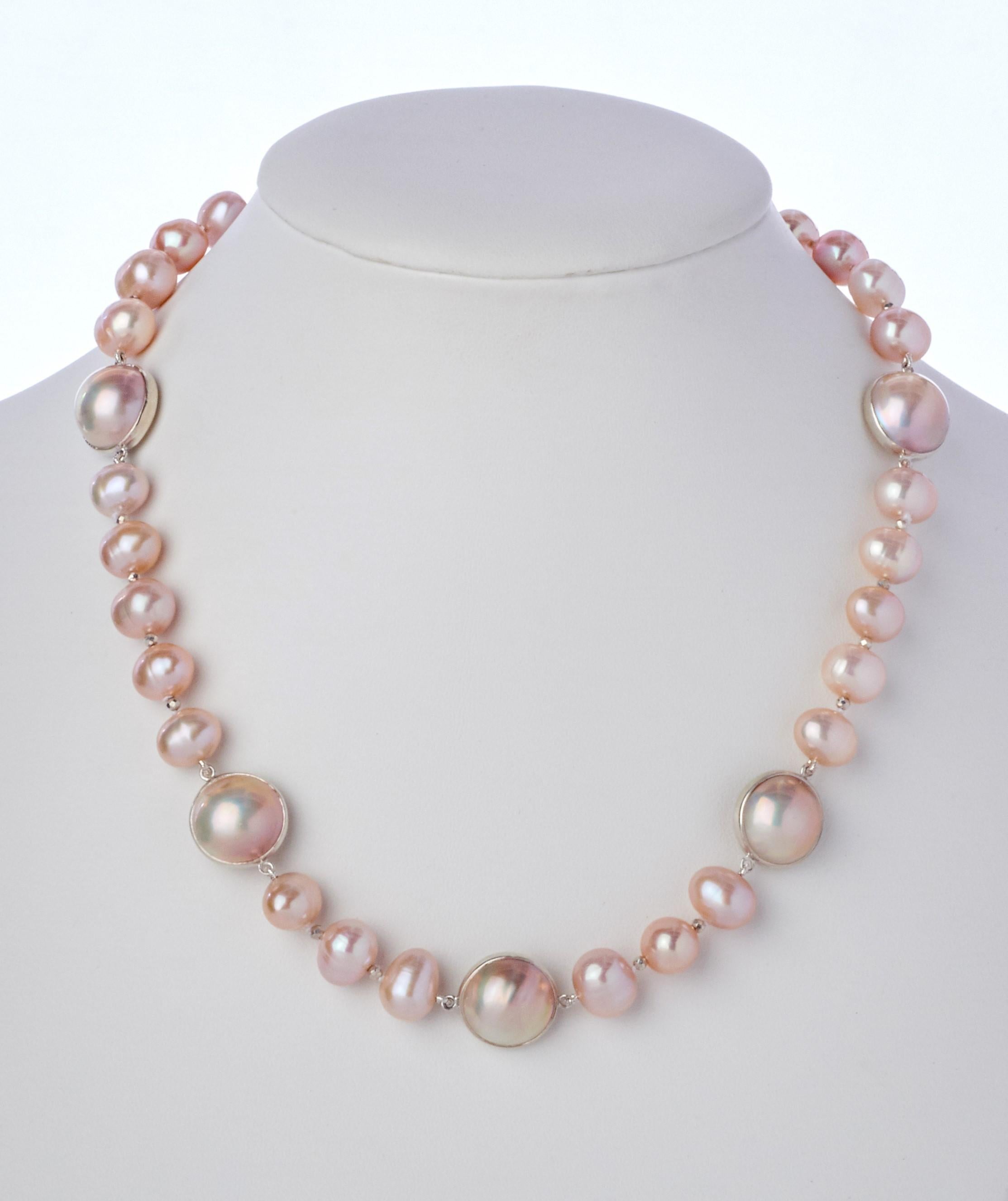 Soft lustrous pink hues with featured white mabe pearl sterling stations create this very pretty 16 inch hand-strung necklace. The strand has thirty 8-1/2 mm blush button pearls which are accented by five 13-1/2 mm white mabe pearls, bezel set in