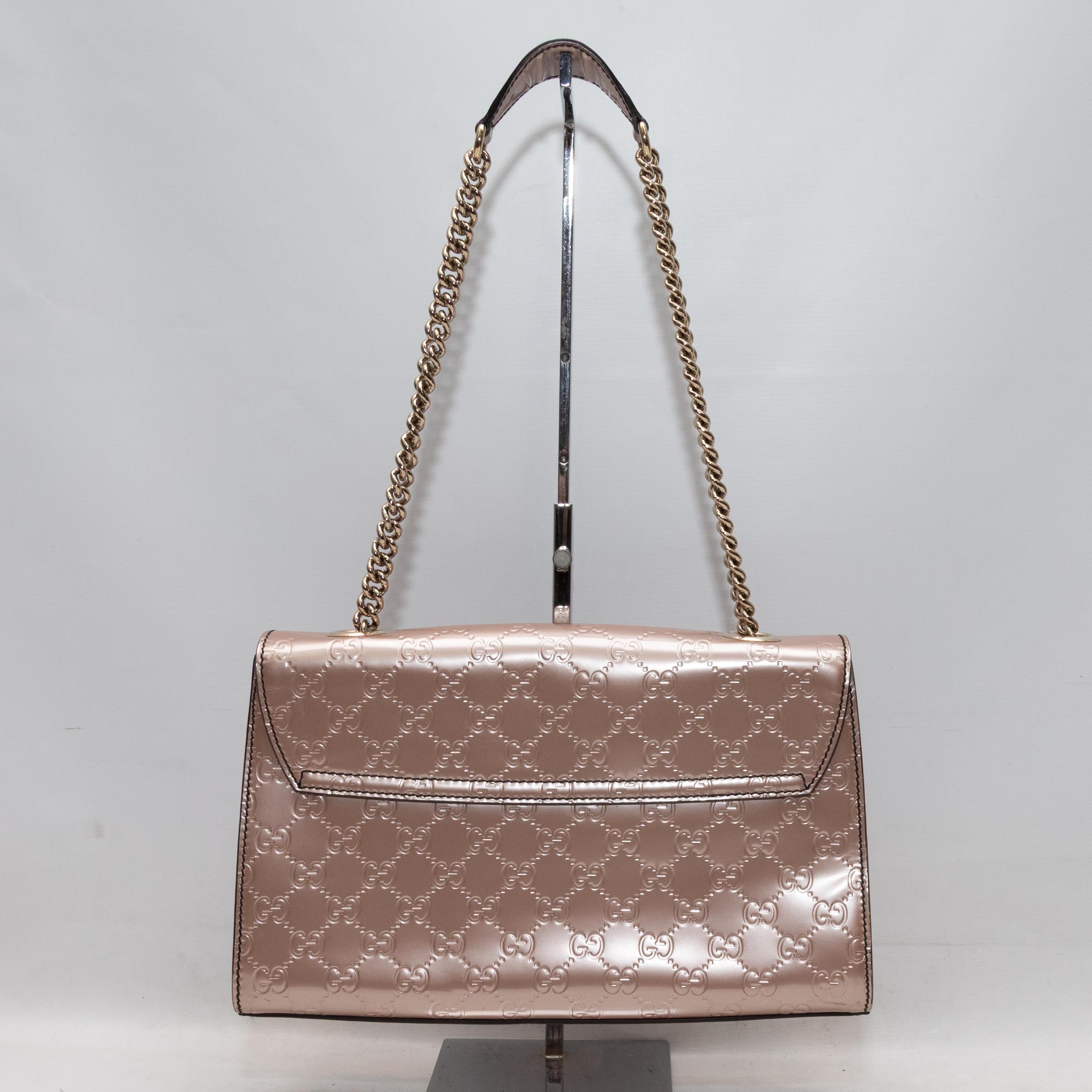 Blush Gucci Metallic Guccissima Emily Handbag. The Emily Handbag features a metallic Guccissima leather body, gold-tone hardware, a chain-link and leather shoulder strap, and a front Horsebit flap closure. 11.75