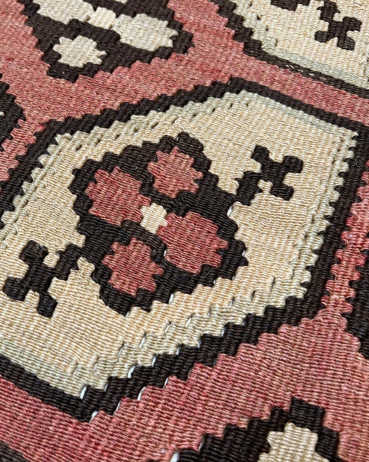 Dieser florale Balkan-Kilim aus den 1960er Jahren verkörpert den Charme und die Handwerkskunst der südosteuropäischen Dorfweberei. Er ist aus handgesponnener Wolle handgewebt und zeigt ein rhythmisches Muster aus stilisierten floralen Medaillons,