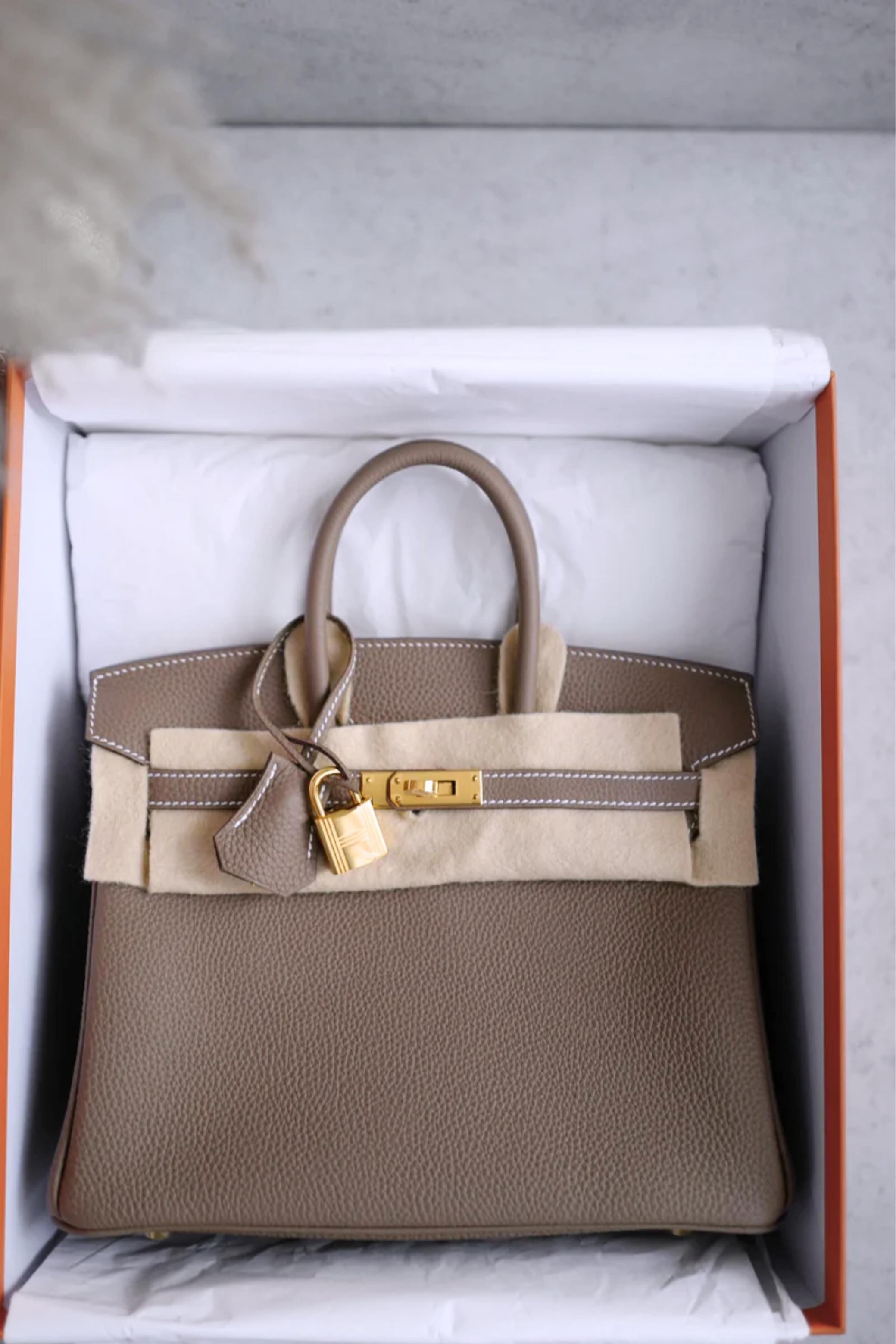 Questa Birkin 25 di Hermes in Togo Etoupe con finiture dorate è semplicemente divina! Questo Gris Etoupe è uno di quei colori neutri di cui non si può fare a meno: è così chic, così versatile e si abbina senza sforzo con tutto, soprattutto con le