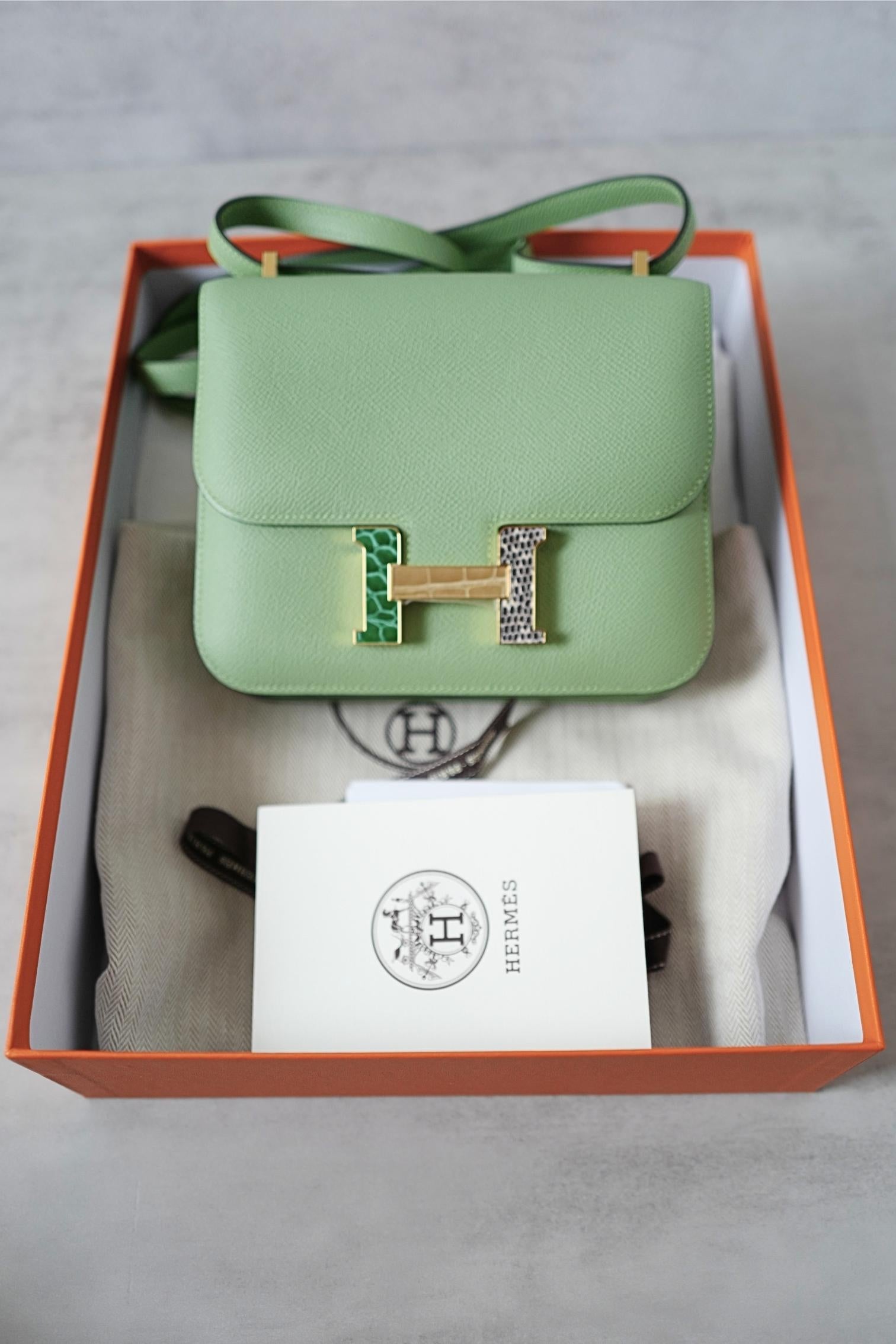 Die Hermès Constance 18 Vert Criquet ist ein Meisterwerk von zeitloser Eleganz und außergewöhnlicher Handwerkskunst. Diese strukturierte Minitasche wurde fachmännisch aus strapazierfähigem Epsom-Leder gefertigt und zeichnet sich durch die für die