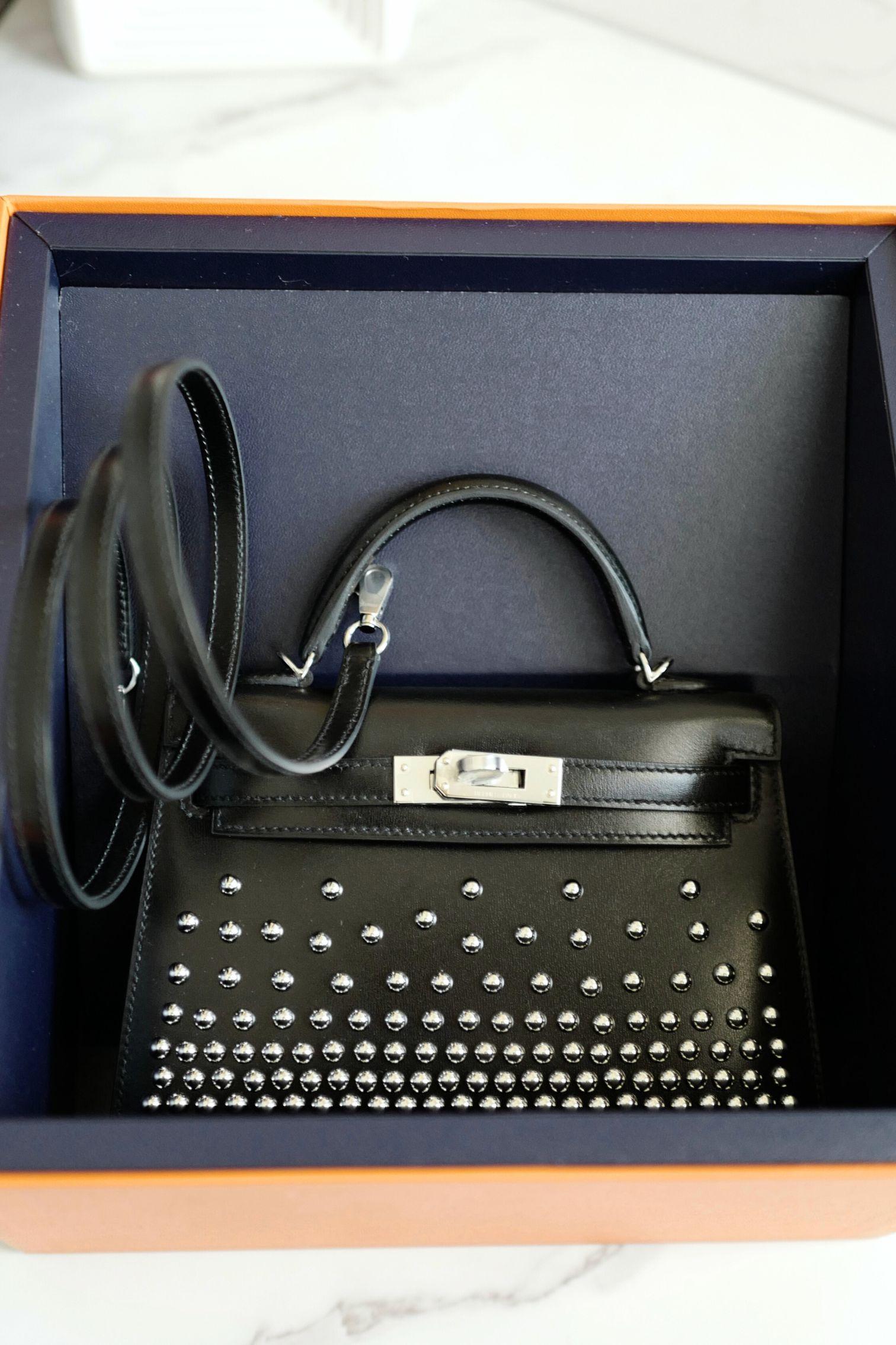 Die Hermès Kelly 20 Clouté mit Palladium-Beschlägen ist eine kühne Variante einer der begehrtesten Ikonen von Hermès. Das kompakte Design ist aus luxuriösem Box-Leder handgefertigt und wird durch polierte Silbernieten aufgewertet, die für eine