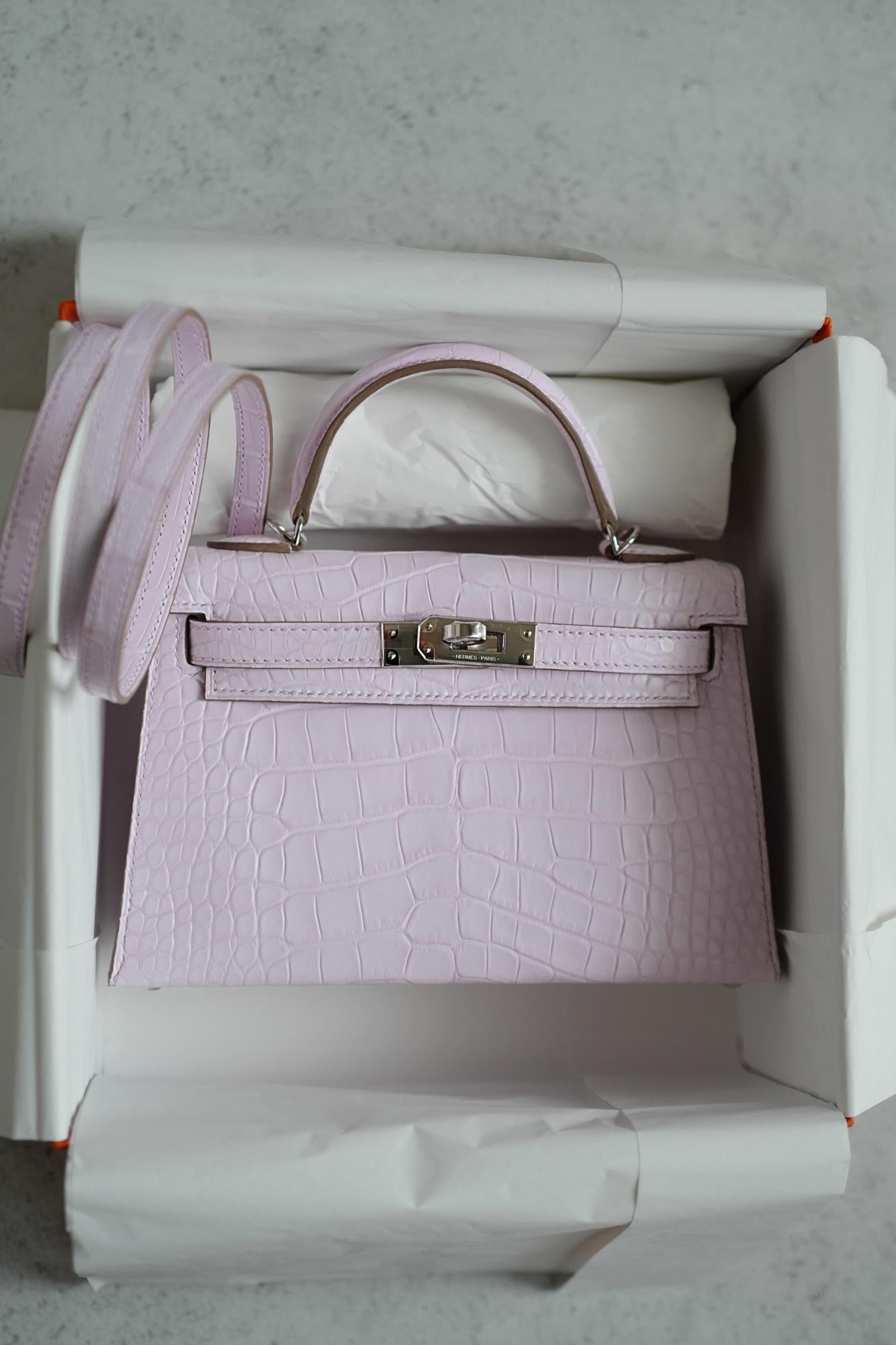 Diese Mini Kelly von Hermès ist ein Hauch von Anmut und Weiblichkeit, eingefangen in der seltenen Schönheit von mattem Alligatorleder. Sein zarter Farbton tanzt zwischen Erröten und Heiterkeit und erinnert an die stille Poesie der Morgendämmerung.