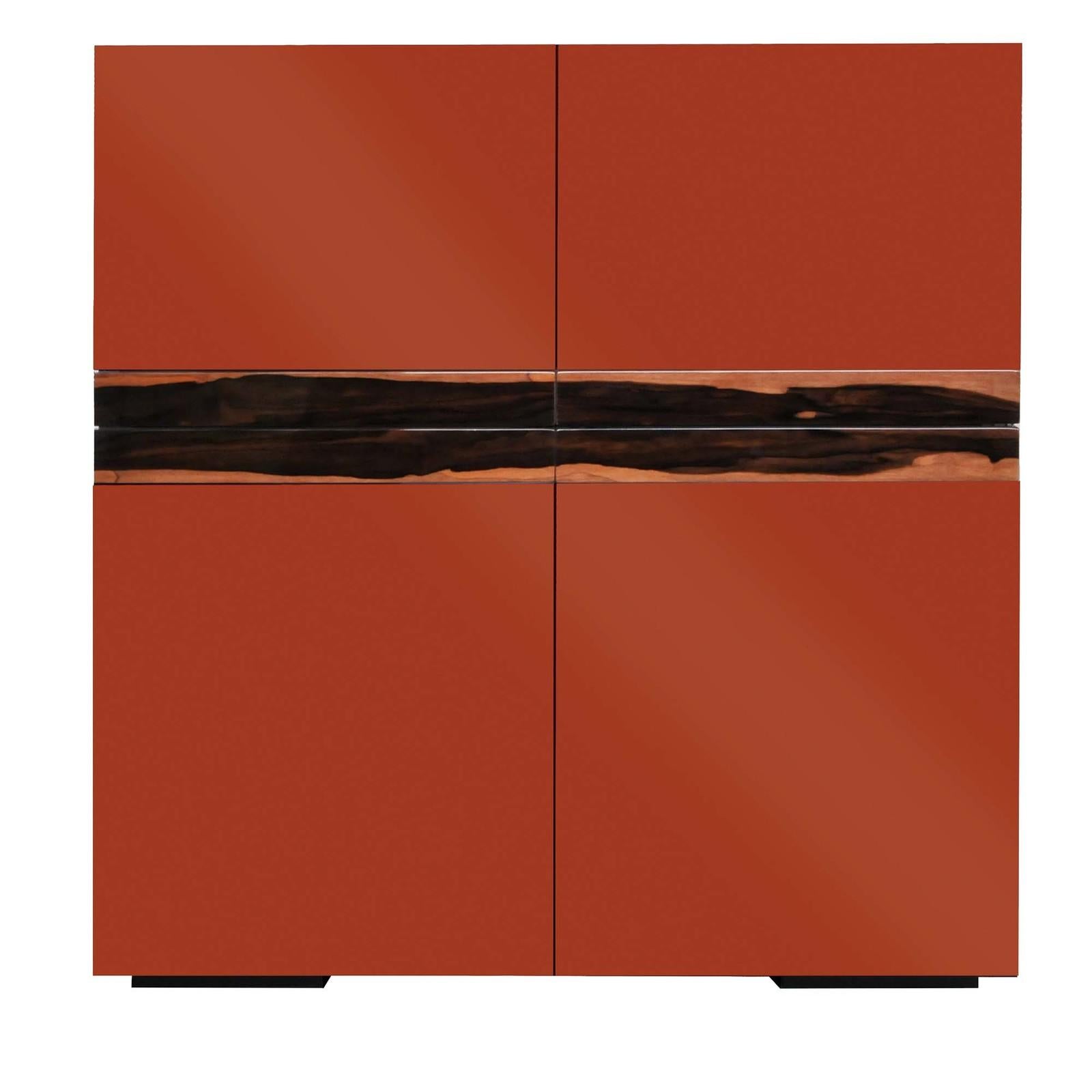 A statement piece in any dining or living room, this bar cabinet combines bold colors in a sleek and essential silhouette enhanced by sophisticated details. The glossy red china polyurethane lacquer is complemented by the warm hues of the Macassar