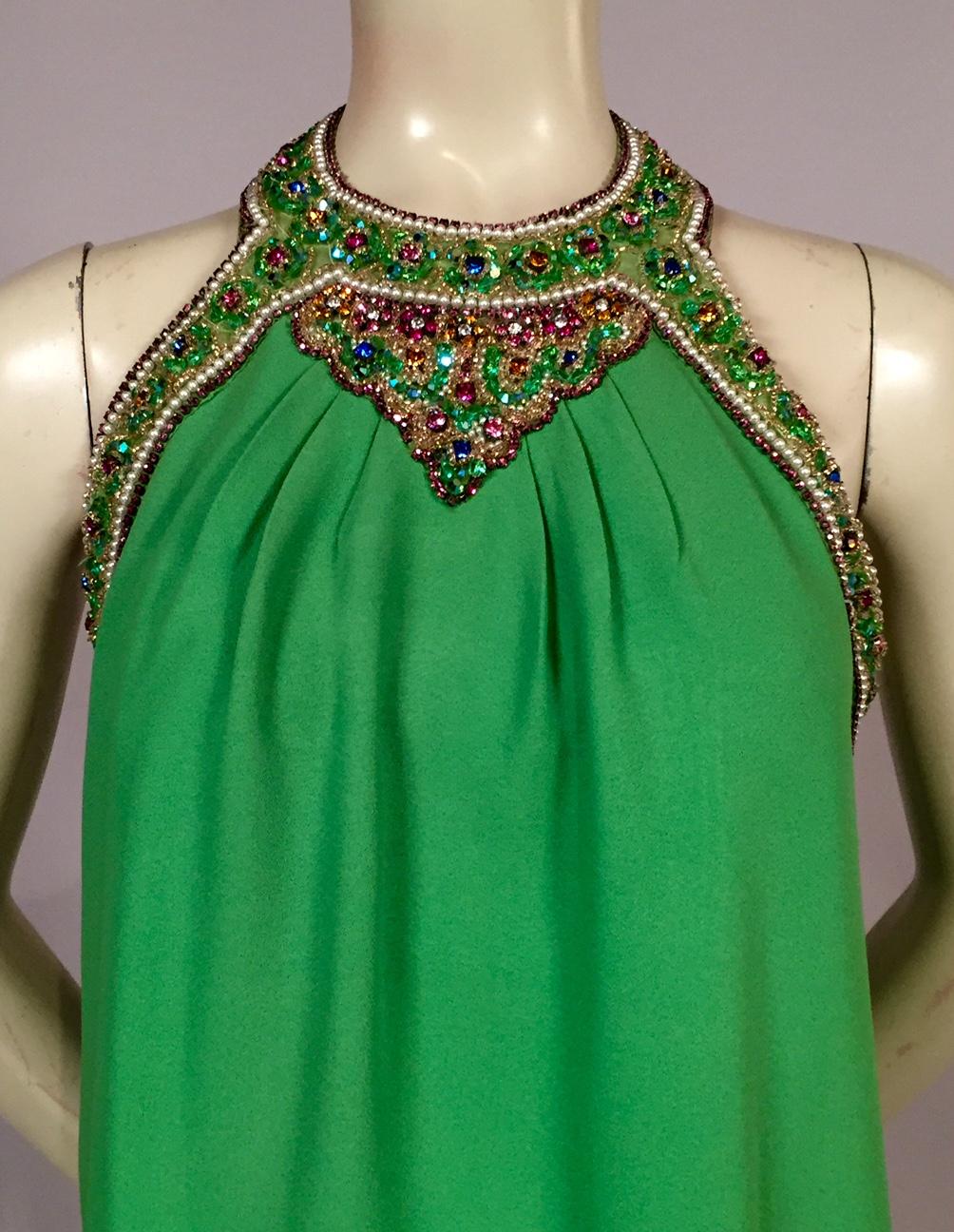 Bob Bugnand has used the most spectacular jewels to decorate the halter neckline of this bright green crepe evening dress. Pearls and prong set pink beads are used to trim all of the edges. A rainbow mix of colors and beads fills every speck of