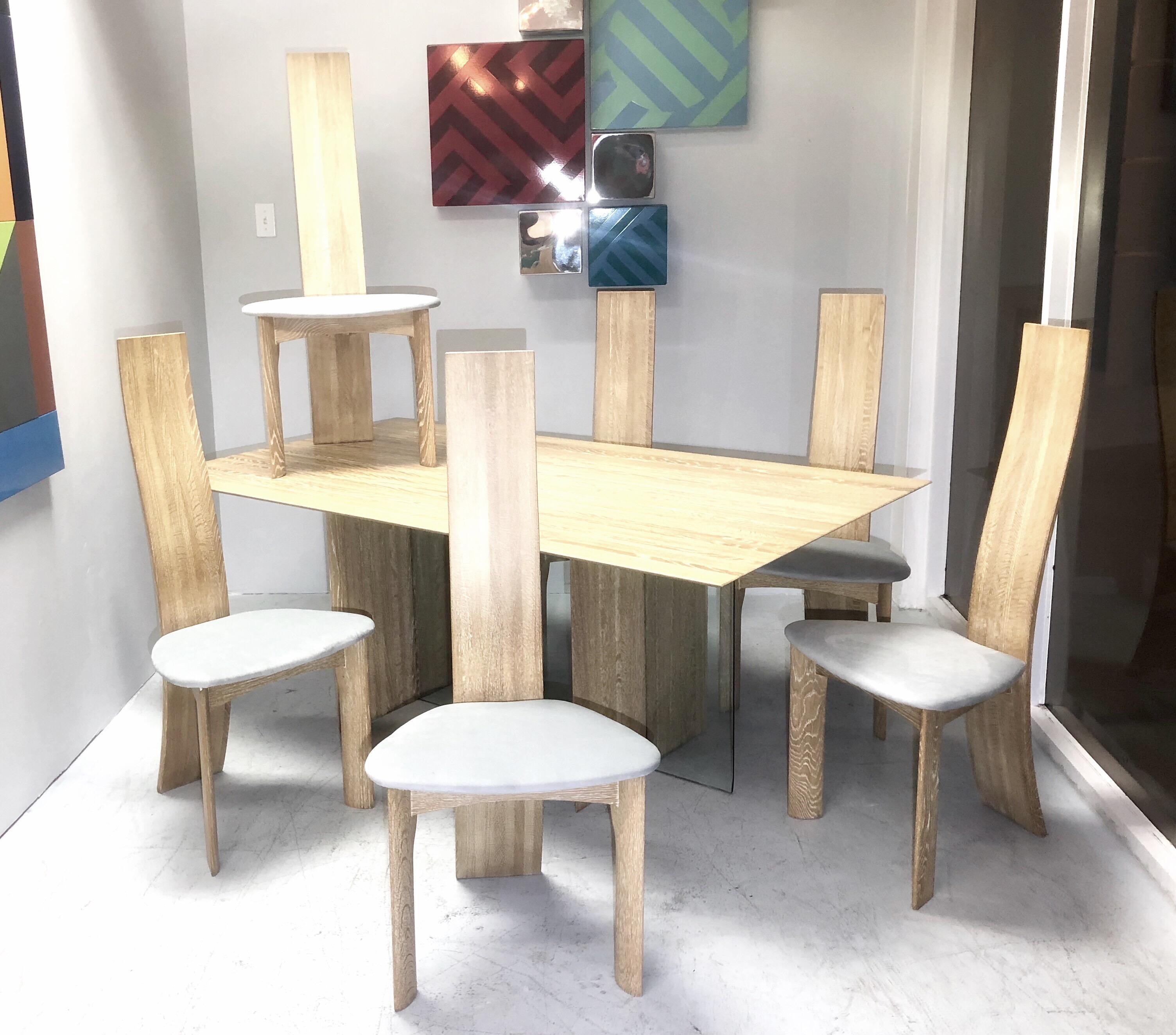 A modern Danish dining set. A solid oak table with a glass inset element on the base. 6 sculptural chairs also of solid oak. The chairs tall backs are slender and end being extremely thin at the top. The look is very sculptural and Minimalist with a