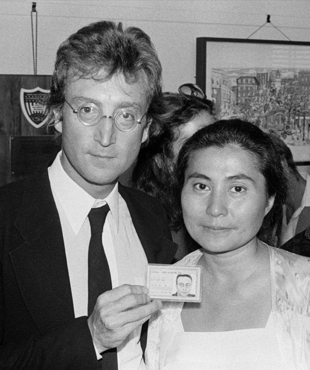 Black and White Photograph de Bob Gruen - John Lennon con su tarjeta verde y Yoko Ono, NYC 1976