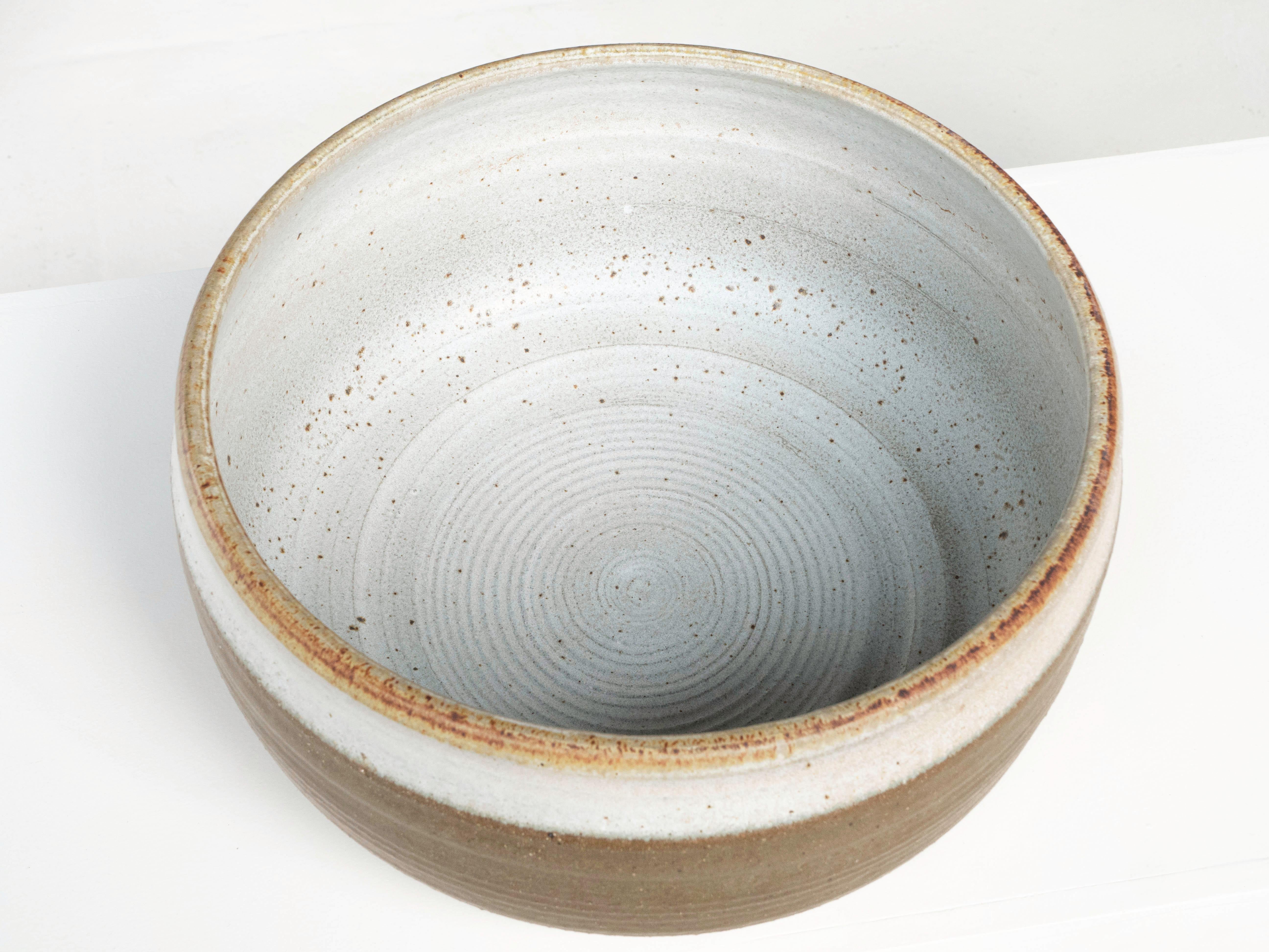 A hand thrown bowl shaped planter by ceramist Bob Kinzie for his company Affiliated Craftsmen, California 1960's. The upper portion of the piece has a dark green glaze with espresso colored specks while the bottom portion shows exposed stoneware.