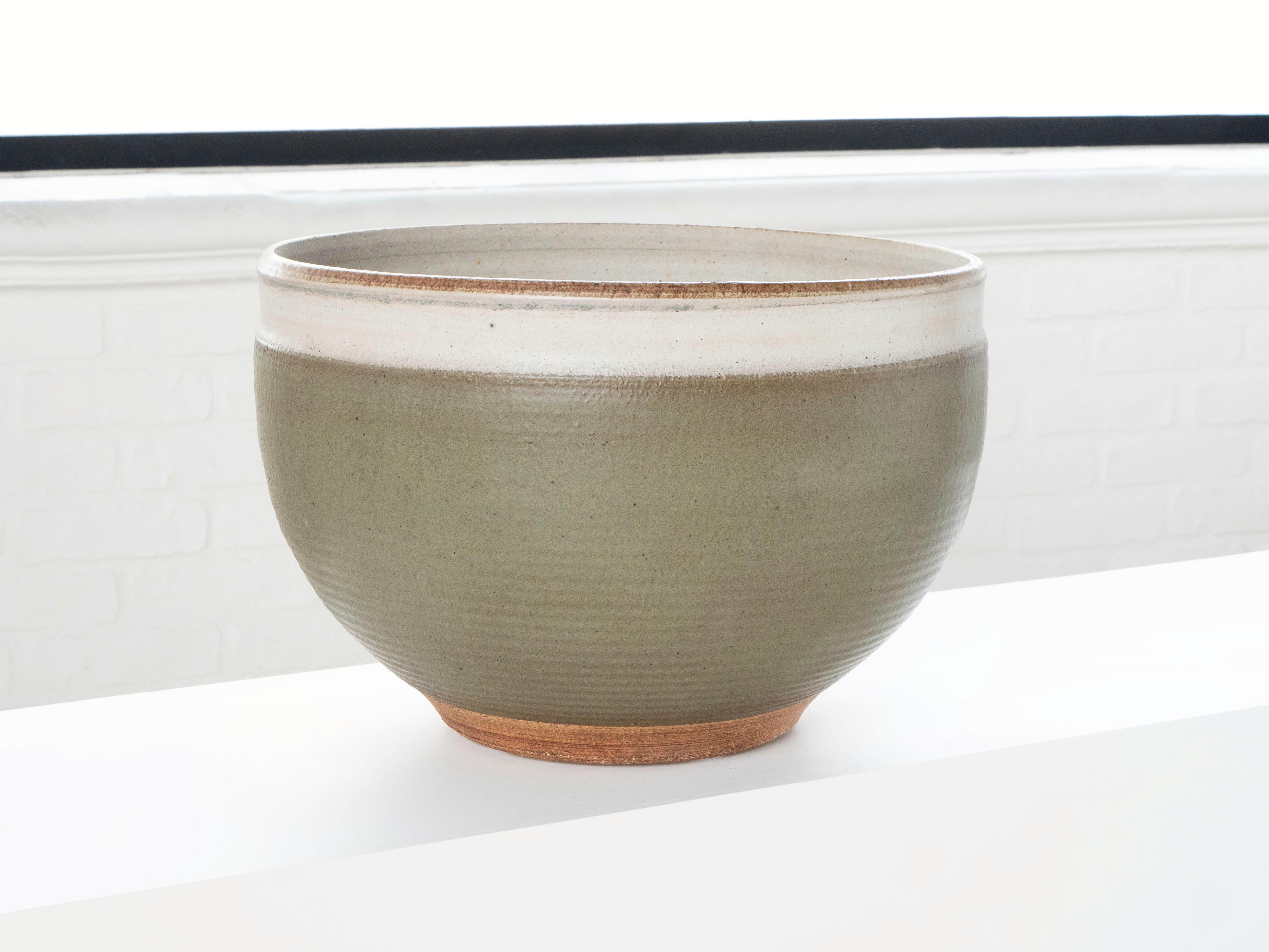 A large hand thrown bowl shaped planter by ceramist Bob Kinzie for his company Affiliated Craftsmen, California 1960's. The upper portion of the piece has a soft green glaze with espresso colored specks while the bottom portion shows exposed