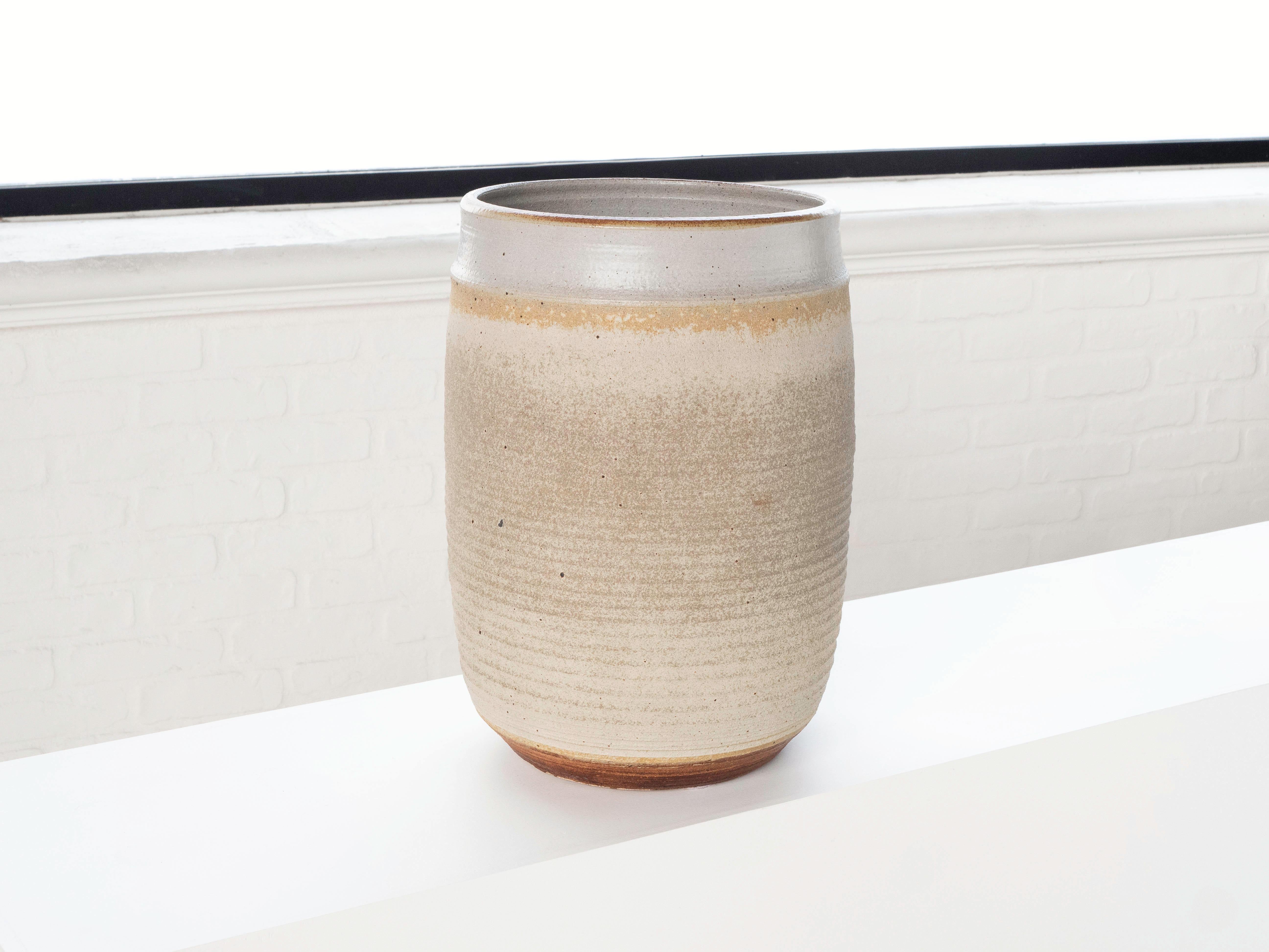 A large hand thrown cylindrical shaped planter by ceramist Bob Kinzie for his company Affiliated Craftsmen, California 1960s. The upper portion of the piece has a neutral tan tone glaze with espresso colored specks while the bottom portion shows