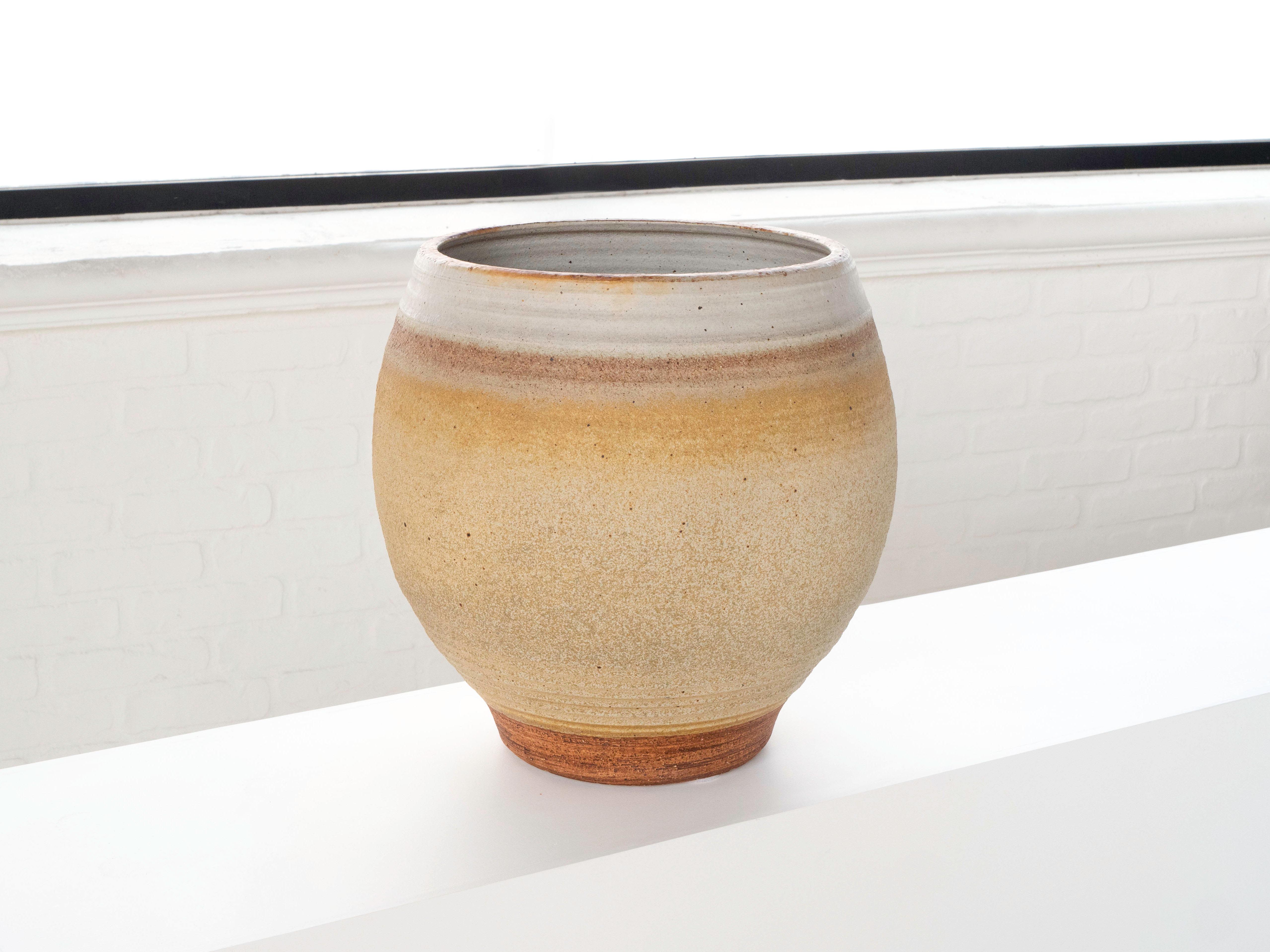 A large hand thrown planter by ceramist Bob Kinzie for his company Affiliated Craftsmen, California 1960's. The upper portion of the piece has a soft yellow tan tone glaze with espresso colored specks while the bottom portion shows exposed