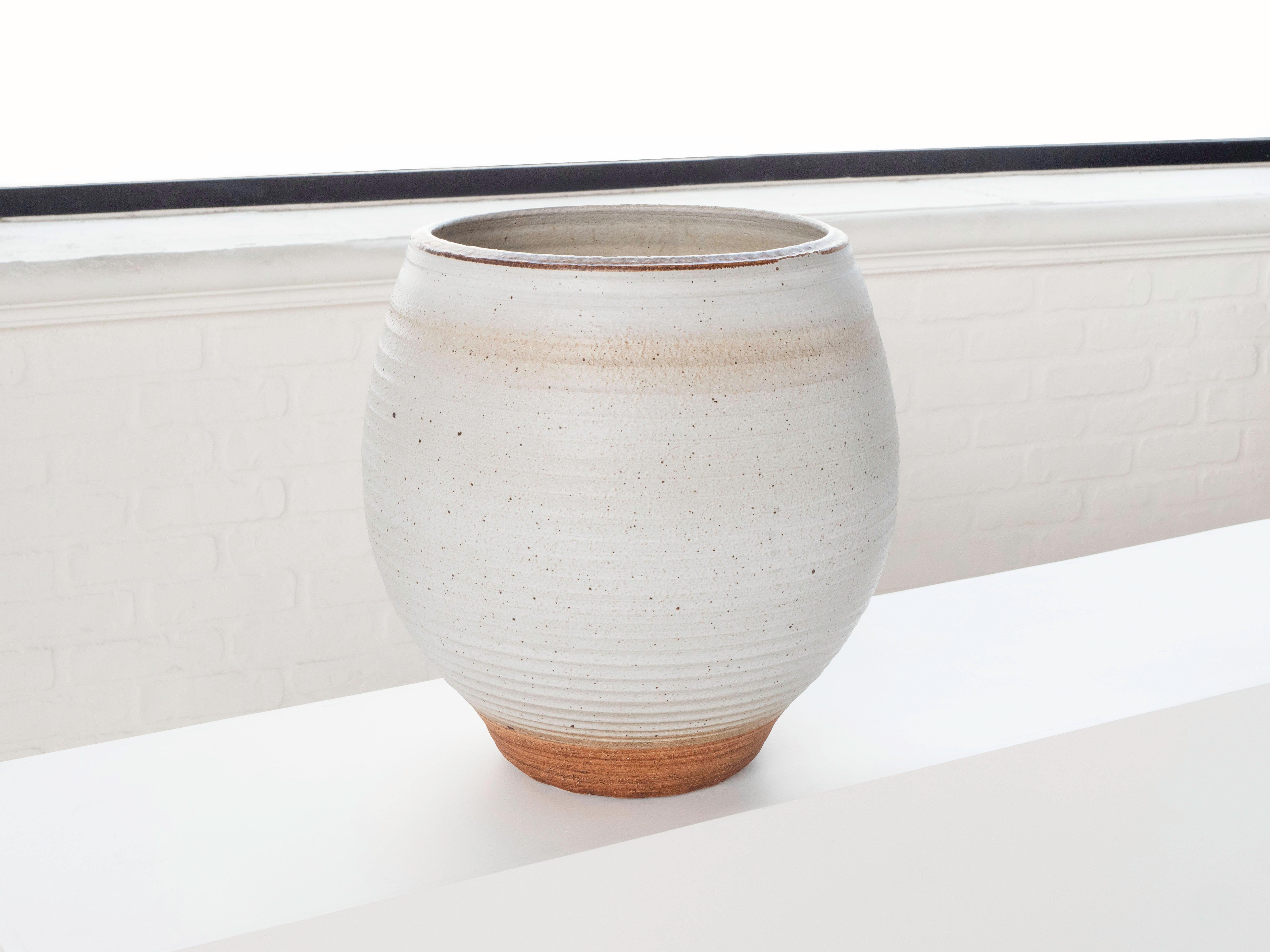 A large hand thrown planter by ceramist Bob Kinzie for his company Affiliated Craftsmen, California 1960's. The upper portion of the piece has a white tone glaze with espresso colored specks while the bottom portion shows exposed stoneware. The