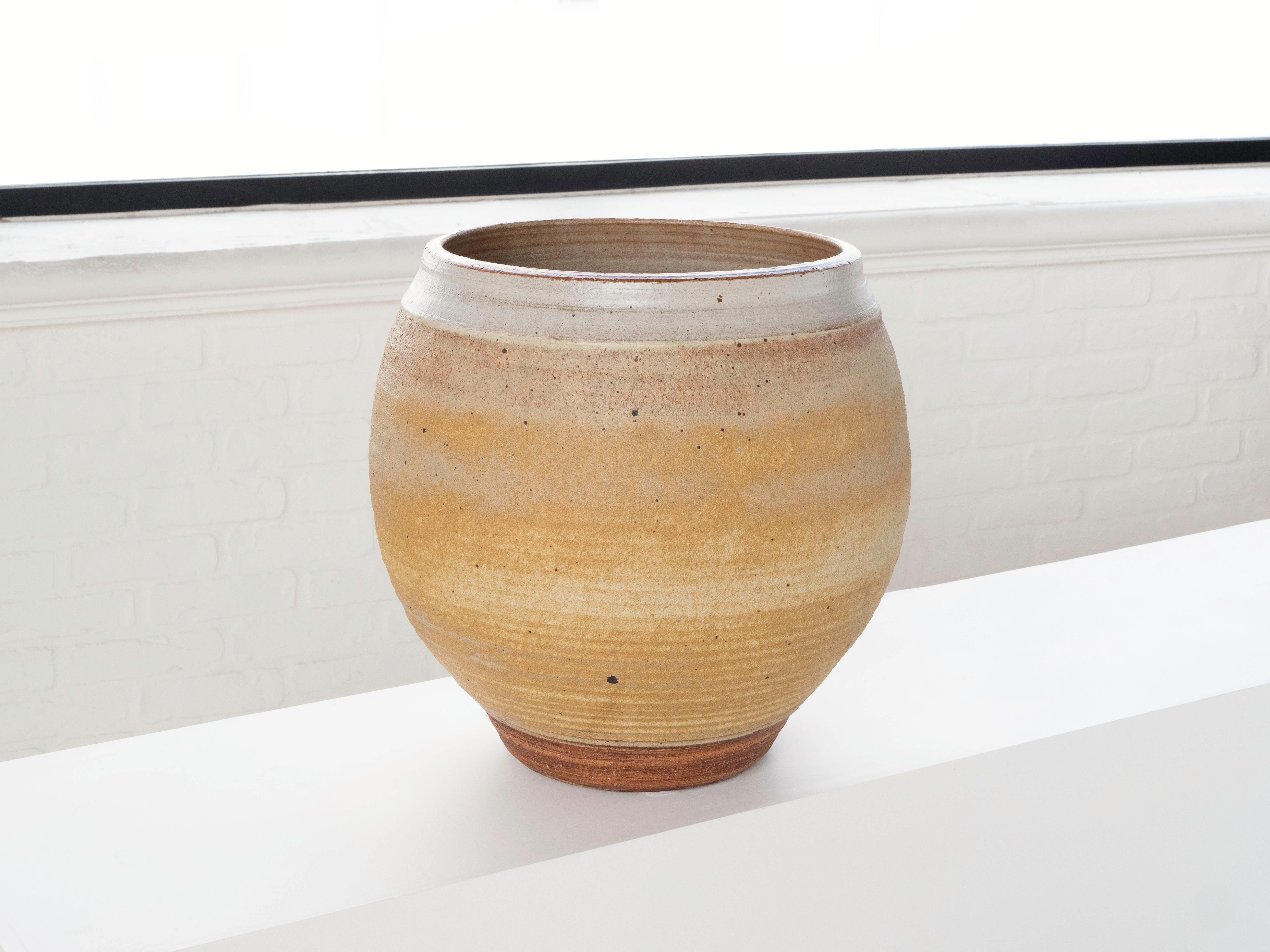 A large hand thrown planter by ceramist Bob Kinzie for his company Affiliated Craftsmen, California 1960's. The upper portion of the piece has a yellow tan tone glaze with espresso colored specks while the bottom portion shows exposed stoneware. The