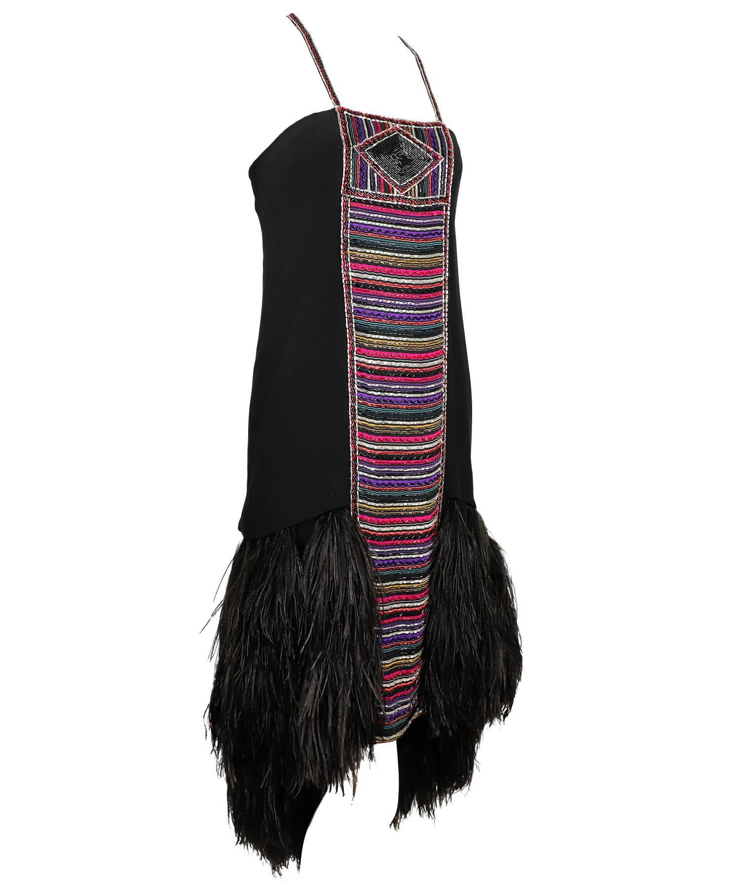 Bob Mackie Couture vintage 1980's is featured in black crepe with multicolored tribal patterned beading at the front and on the straps, which have a hook-and-eye feature at the center back, with a high-low feather hem. Dress features a double