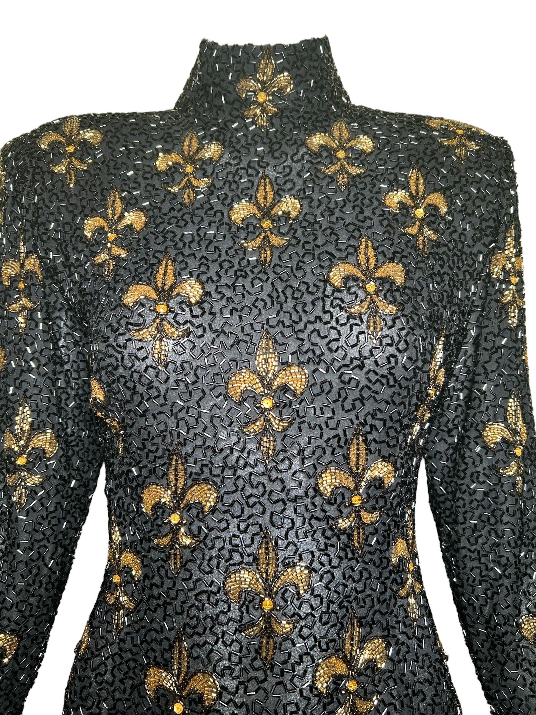 Bob Mackie Fleur de Lys Beaded Long Sleeve Cocktail Gown. Decorated with a fleur de lys design of golden beads with a high neck and long sleeves with zippers. Complete with a back zipper for ease and a dramatic side leg slit for a sexy flair. 