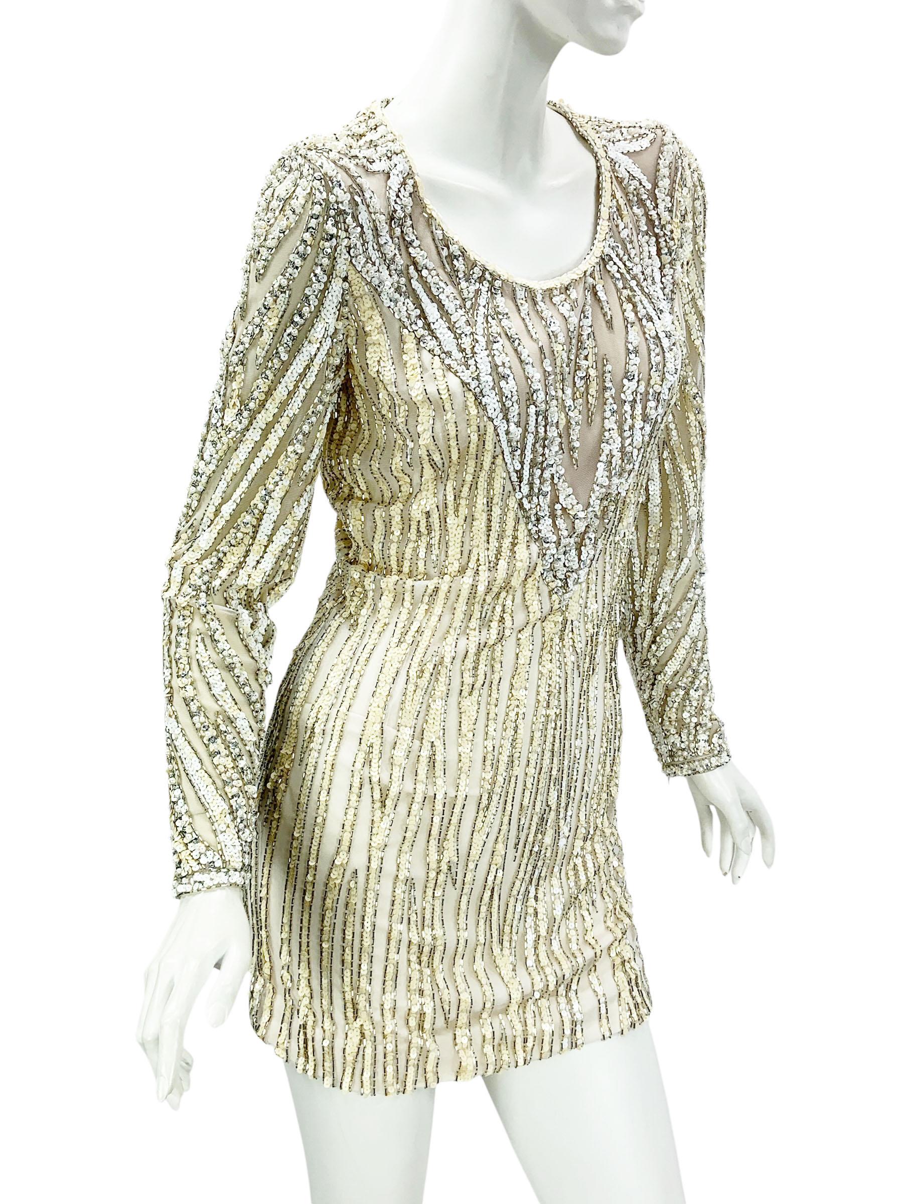 Un exquisito minivestido vintage de Bob Mackie, que muestra el glamour y el arte característicos del diseñador. 
Esta llamativa pieza está totalmente adornada a mano con cascadas de lentejuelas blancas, plateadas y amarillas, cuentas plateadas y