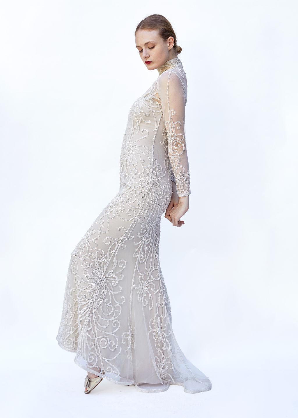 Step into timeless elegance with this exquisite Bob Mackie white mesh gown, designed to captivate and command attention at any event. This stunning gown features intricate beadwork that shimmers with every move, complemented by sheer, long sleeves