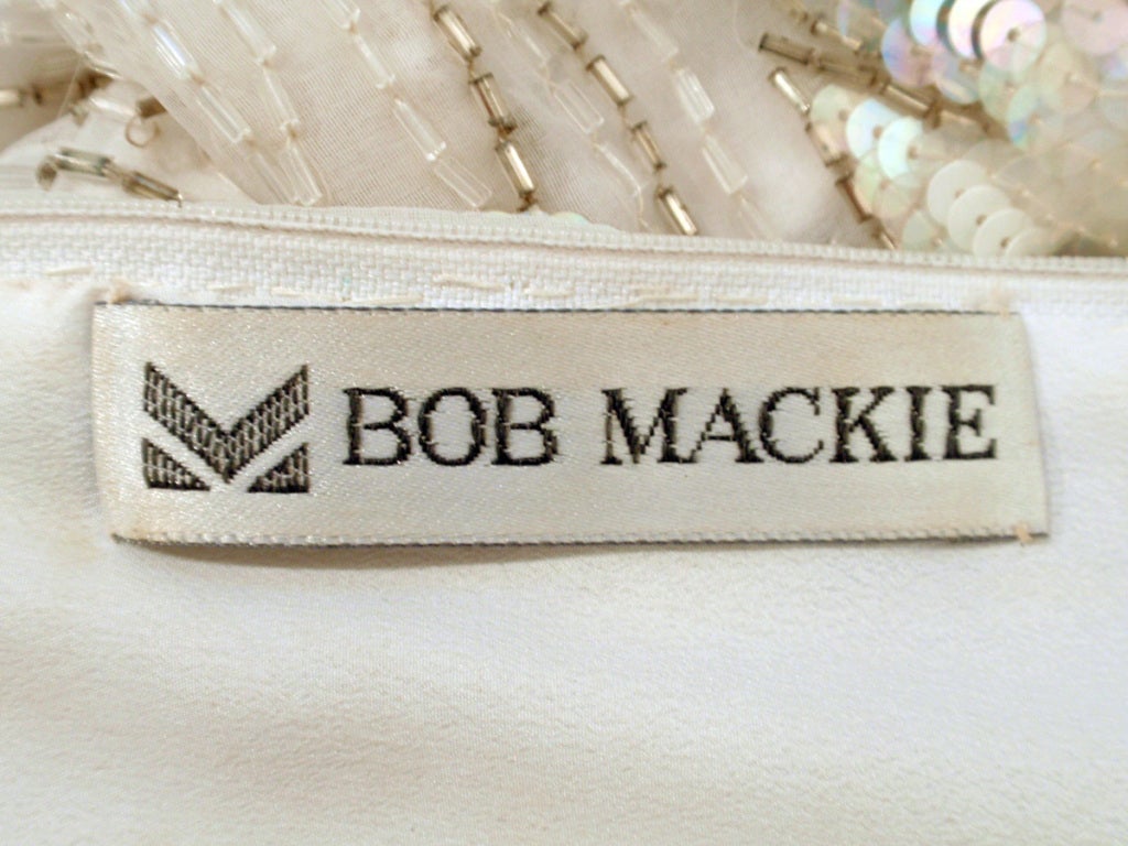 Bata blanca de manga larga Bob Mackie, con ondas de cuentas y lentejuelas moradas y azules.
Se trata de un precioso pedido especial Bob Mackie. Es de color blanco con lentejuelas y abalorios blancos, verdes, verde azulado y morados que caen en