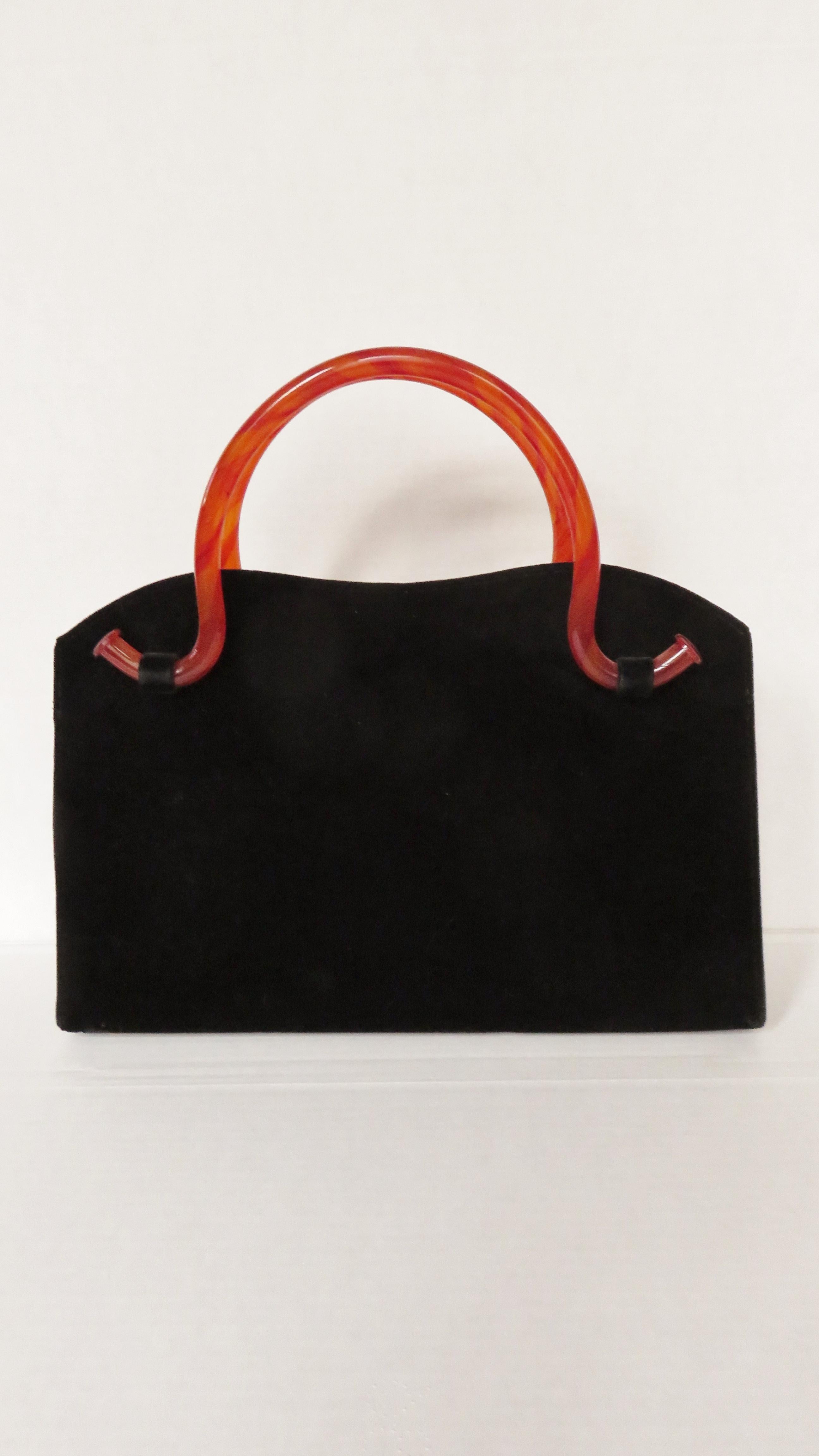 A gorgeous rich black silk velvet handbag with rounded deep orange Bakelite top handles.  It has a gently curved top and gold clasp closure. The bag is lined in black silk with 2 Inside pockets, one zippered.

Height  9